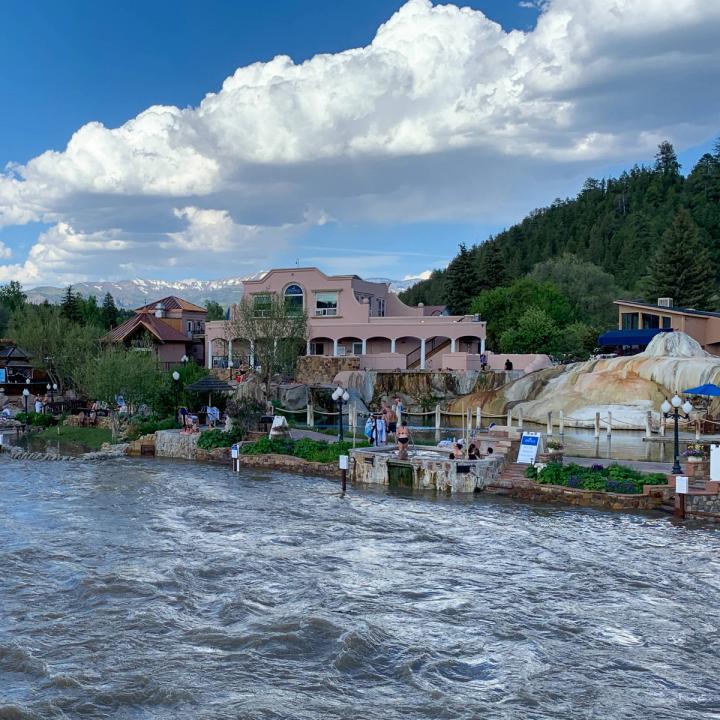 The Springs Resort bathhouse and hot tubs in the background and the raging San Juan River in the foreground