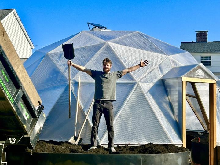 Ben Barkan filling a raised bed outside a Growing Dome greenhouse