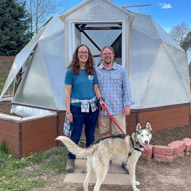 Image of Growing Spaces' Creative Director, Laura Dollar, her husband and dog, outside a 15' Growing Dome.
