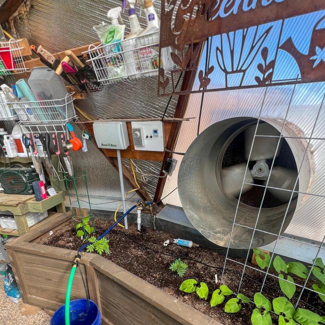 Solar chill swamp cooler in a greenhouse with electrical panel and miscellaneous garden supplies