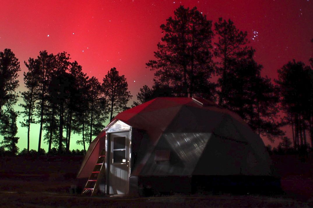 Bright red and green northern lights visible behind a Growing Dome Greenhouse