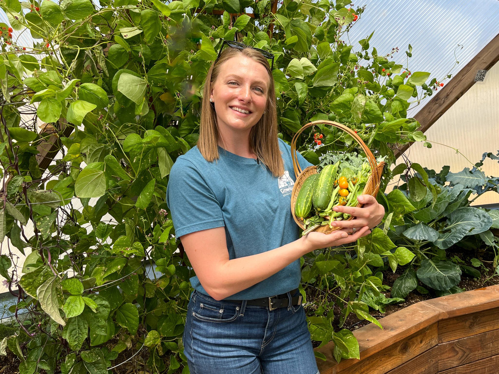 Woman holding a basket of produce grown in a Growing Dome greenhouse
