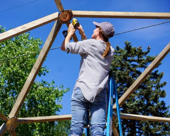 Young lady learning how to build a geodesic dome greenhouse from growing spaces during a volunteer event for go farm in golden, CO.