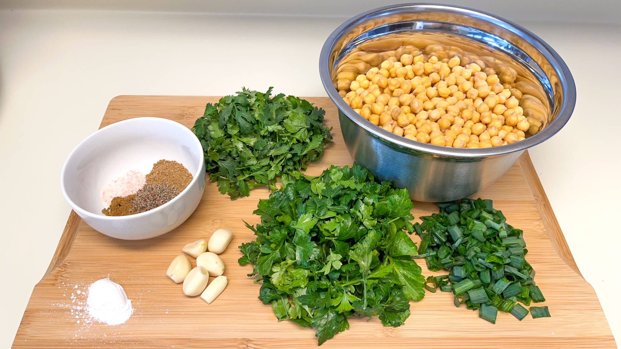 falafel ingredients laid out on a cutting board herbs and spices soaked chickpeas baking powder