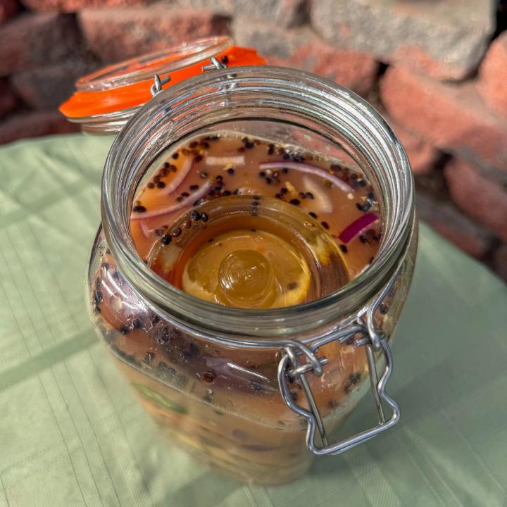 Glass weight resting in a jar filled with a fire cider recipe