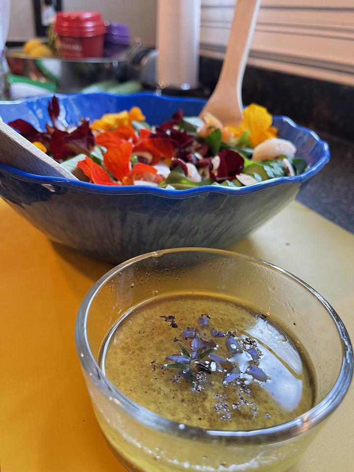 Shrimp and Nasturtium Salad Dressing in a small bowl in the foreground, large serving bowl of salad in the background