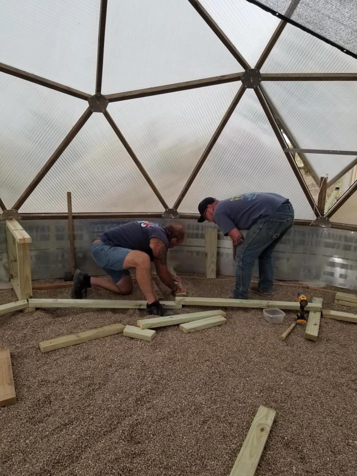 people workign inside a geodesic greenhouse Probst dome construction help
