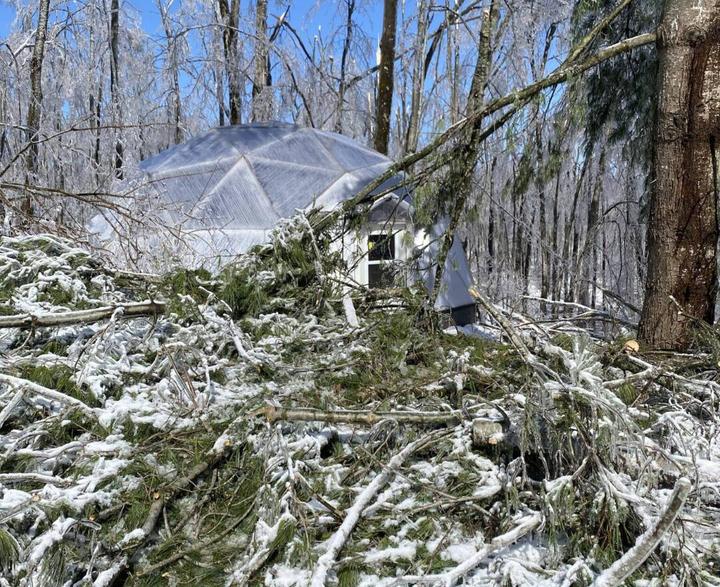 A 26' Growing dome with large amount of fallen tree branches in front of it