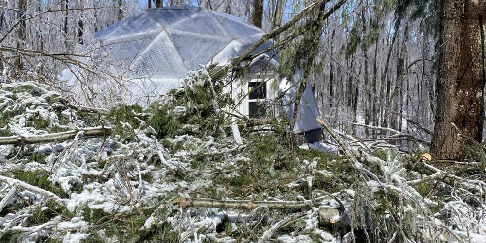A 26' Growing dome with large amount of fallen tree branches in front of it