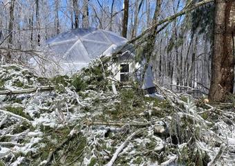 A 26' Growing dome with large amount of fallen tree branches in front of it