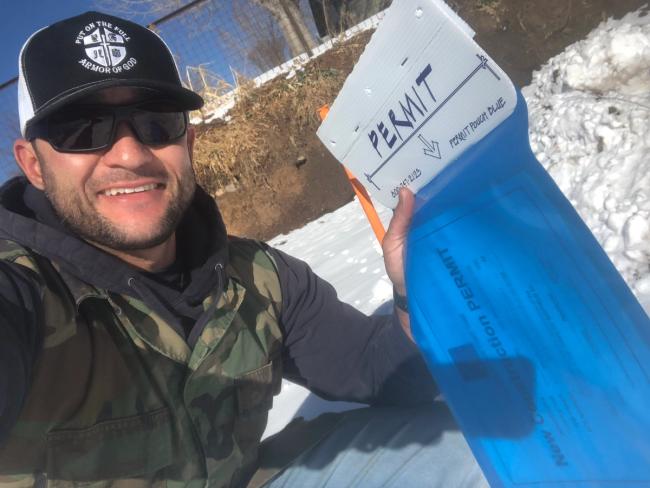 man smiling and holding a permit