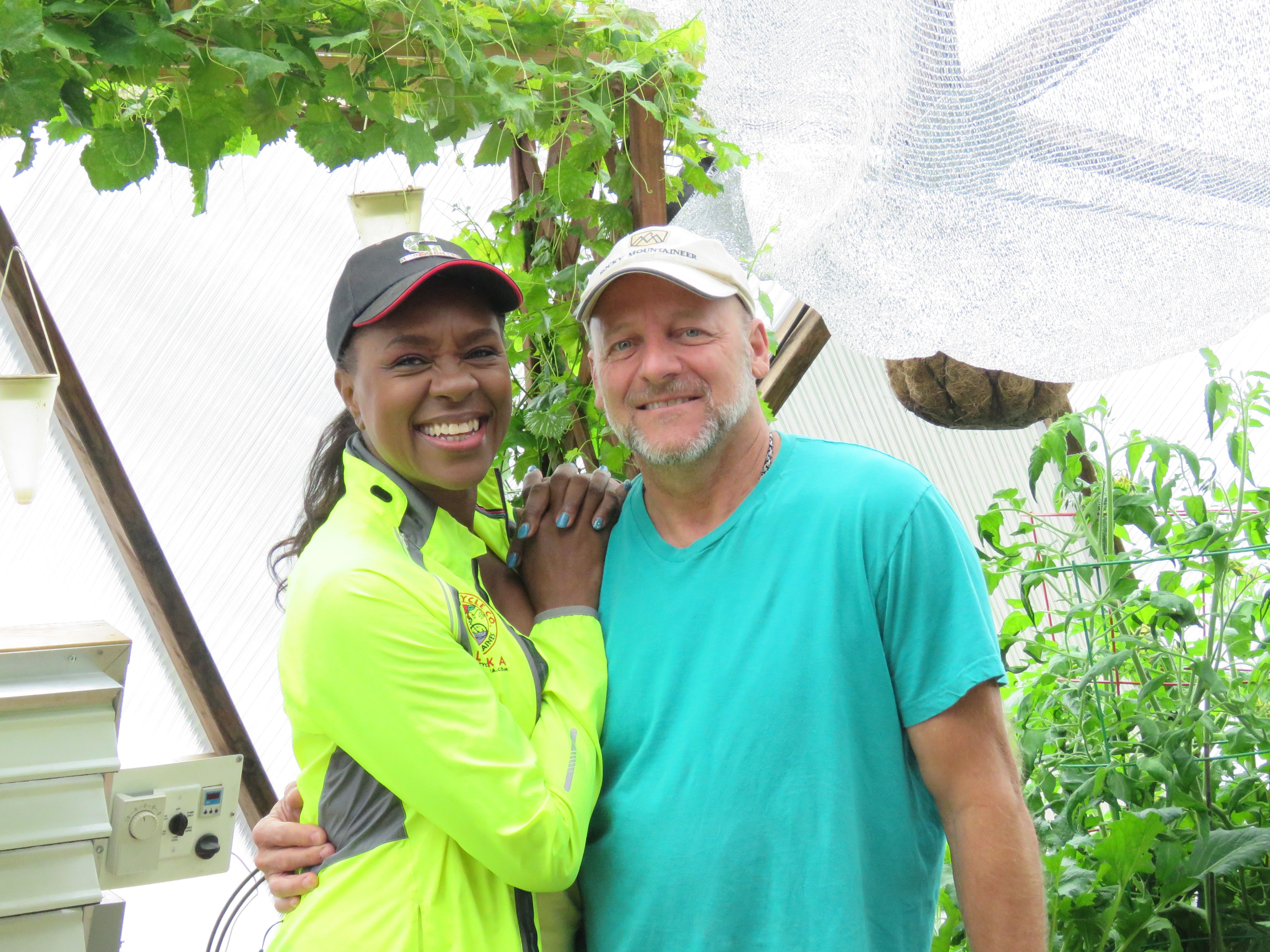 Man and woman smiling and posing in their greenhouse