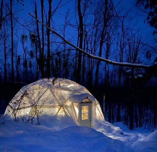 Khris and Allen Nedam's 26-foot Growing Dome glowing at night in the Northern Michigan snow