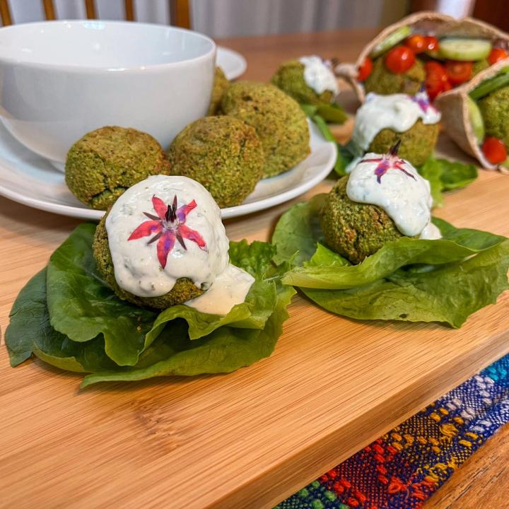 falafel topped with tzatziki and garnished with pink borage flowers on lettuce wraps