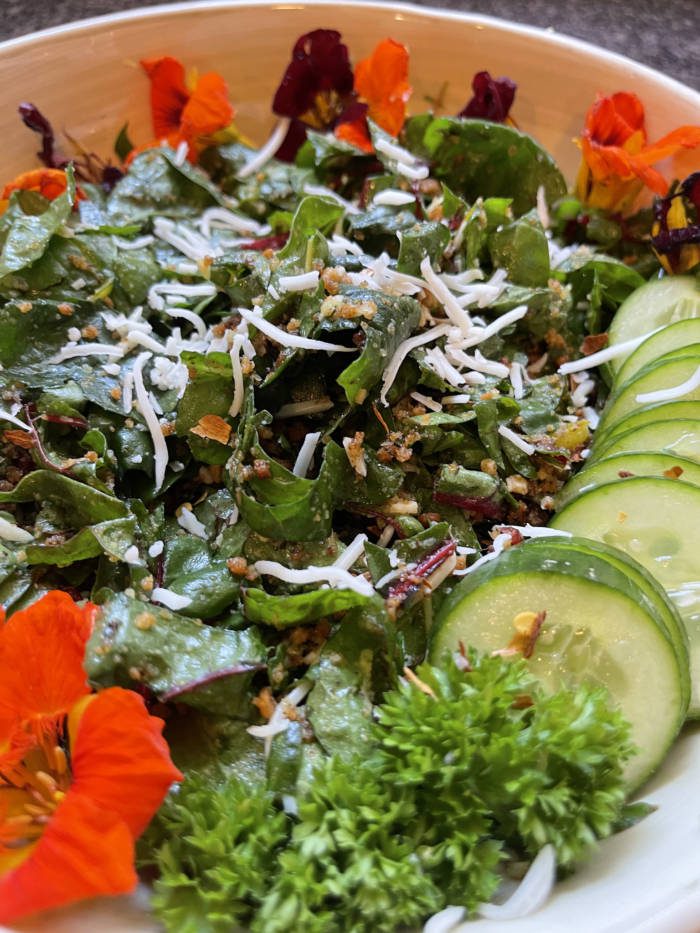 completed salad on a pretty plate with orange edible flowers