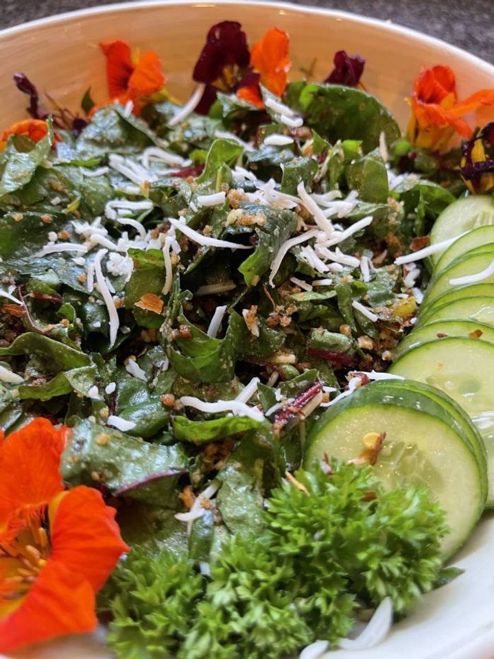 completed salad on a pretty plate with orange edible flowers