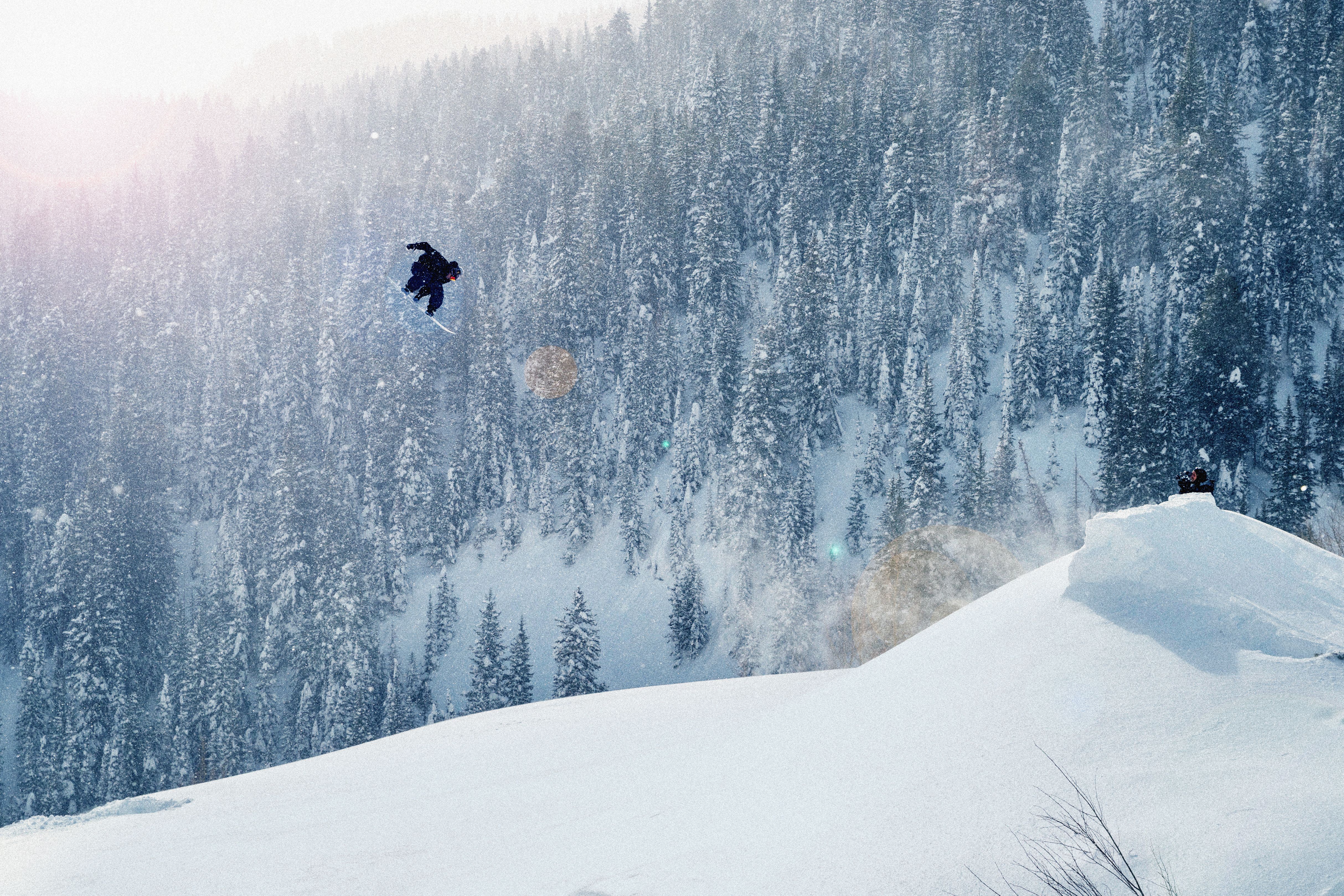 sonwboarder salta foresta innevata