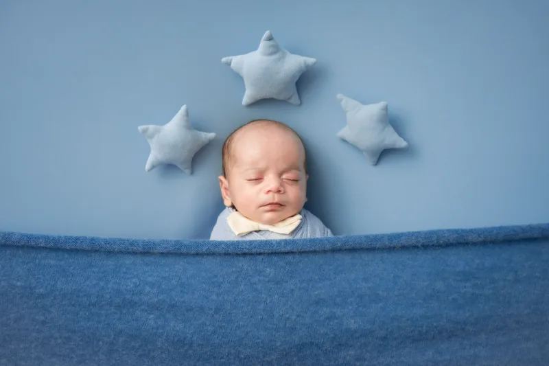 newborn boy sleeping peacefully under blue blanket