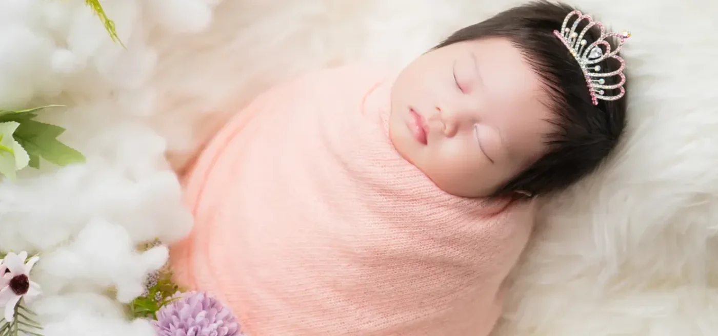 tiny girl newborn photo in pink clothes dreaming