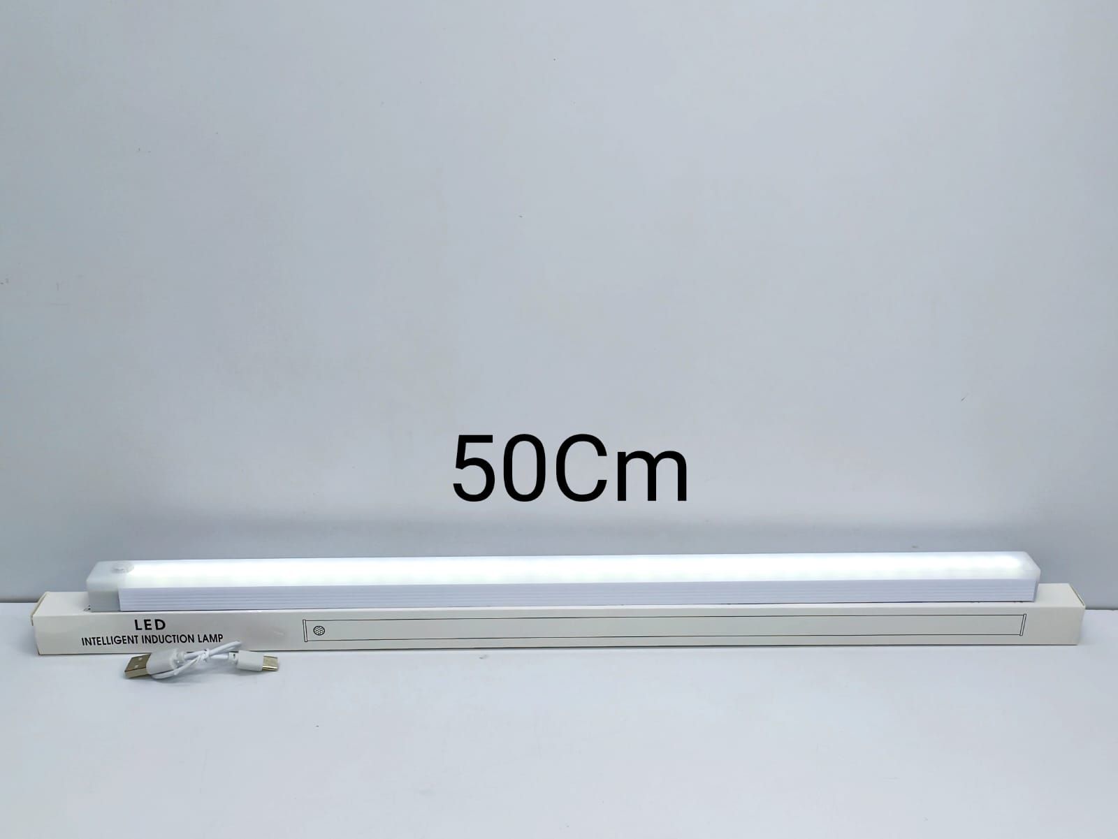 Luz LED recargable con sensor de movimiento de 50 cm encendida, sobre su caja, con el cable USB-C
