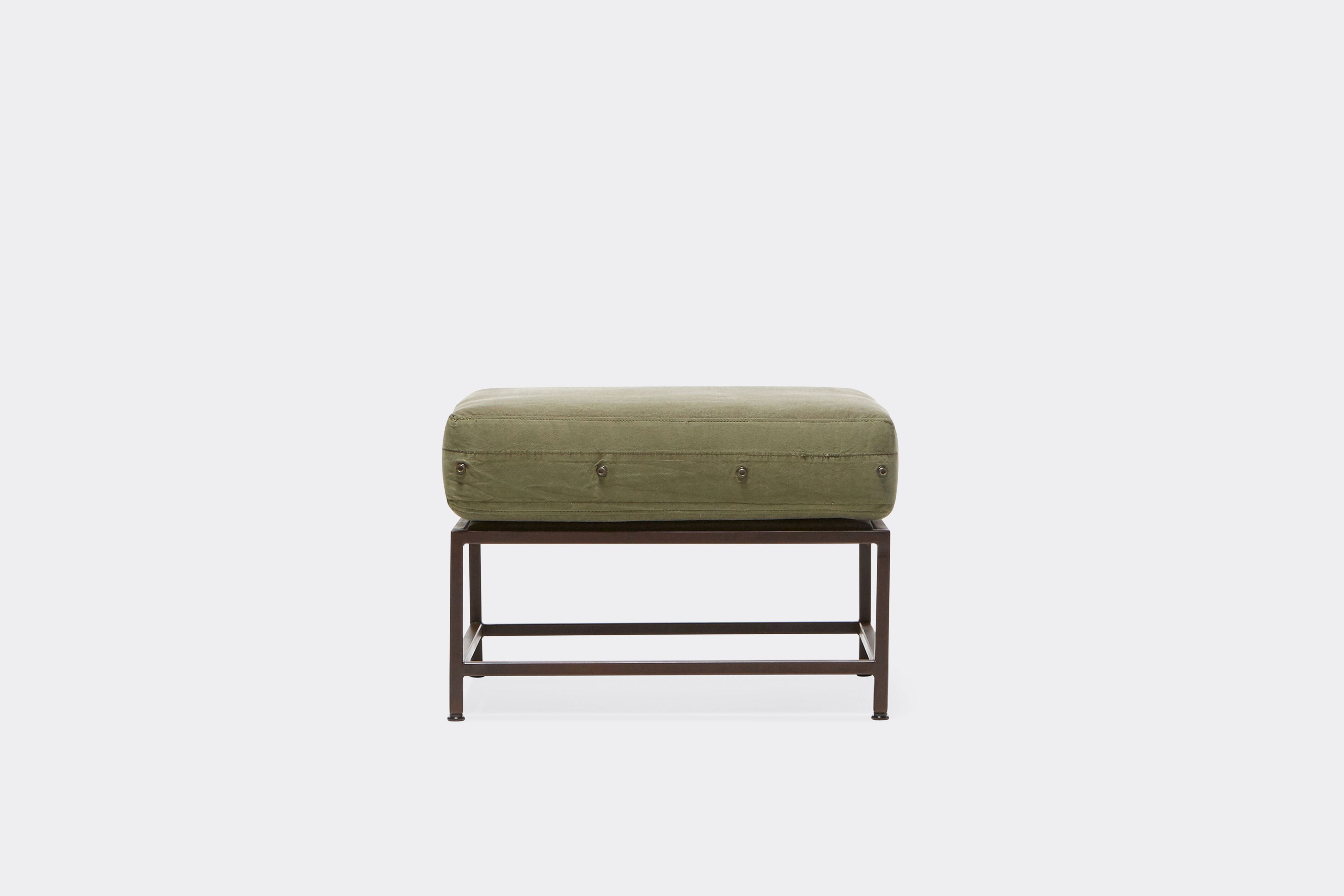 front of ottoman with green canvas upholstery on marble rust metal frame