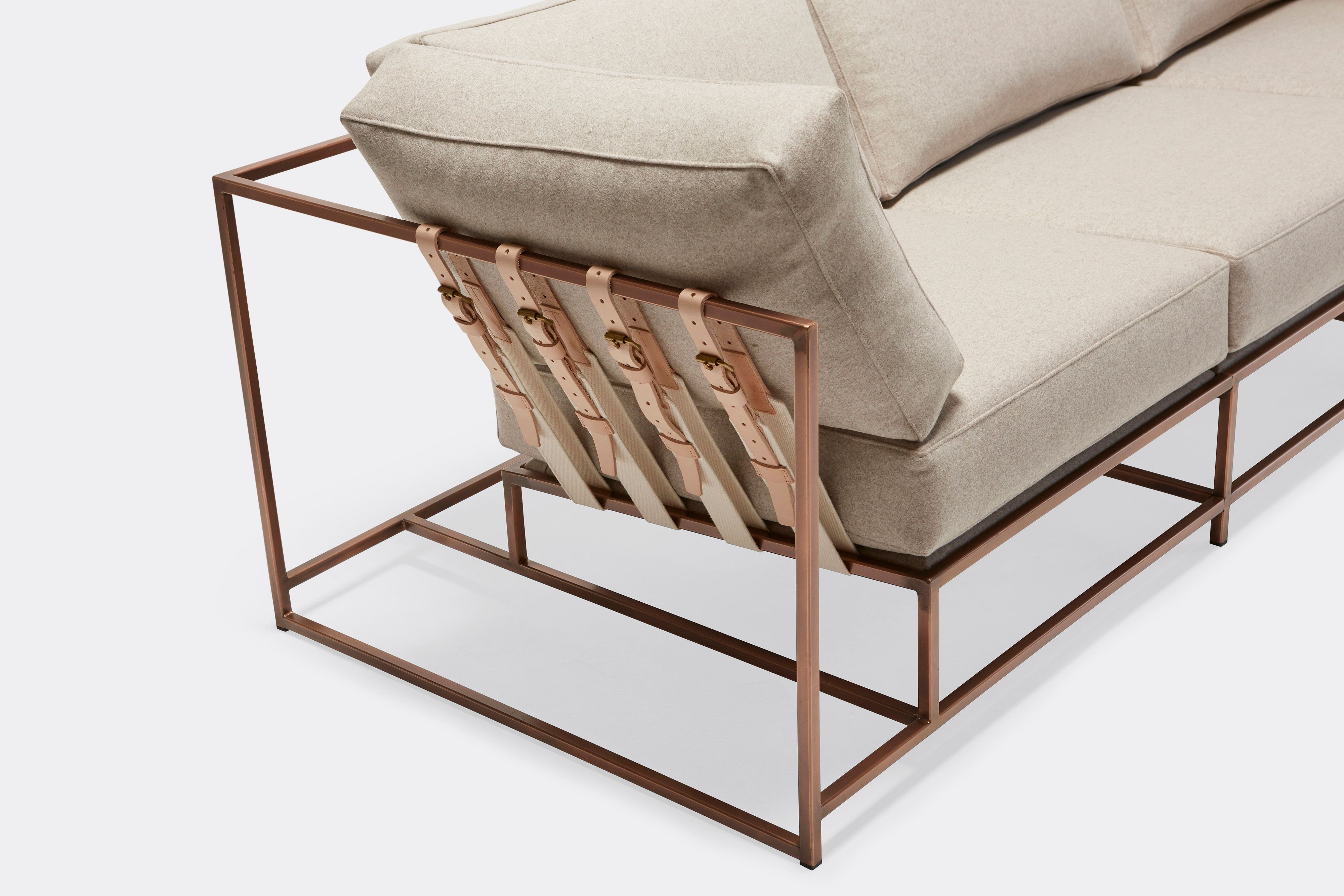 overhead of three piece sofa with cream wool upholstery and natural tan leather belts on antique copper metal frame