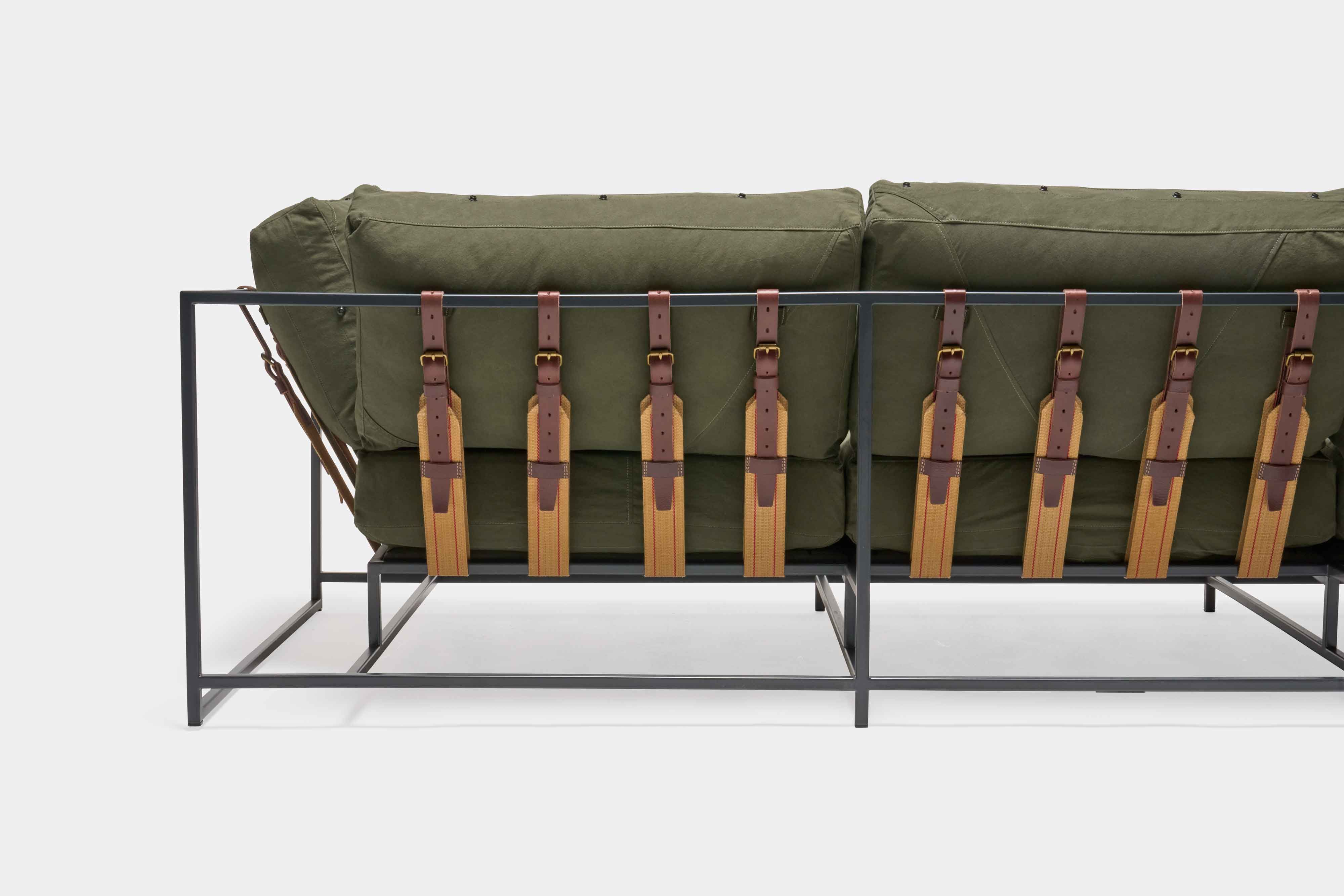 a green couch with a metal frame and leather straps