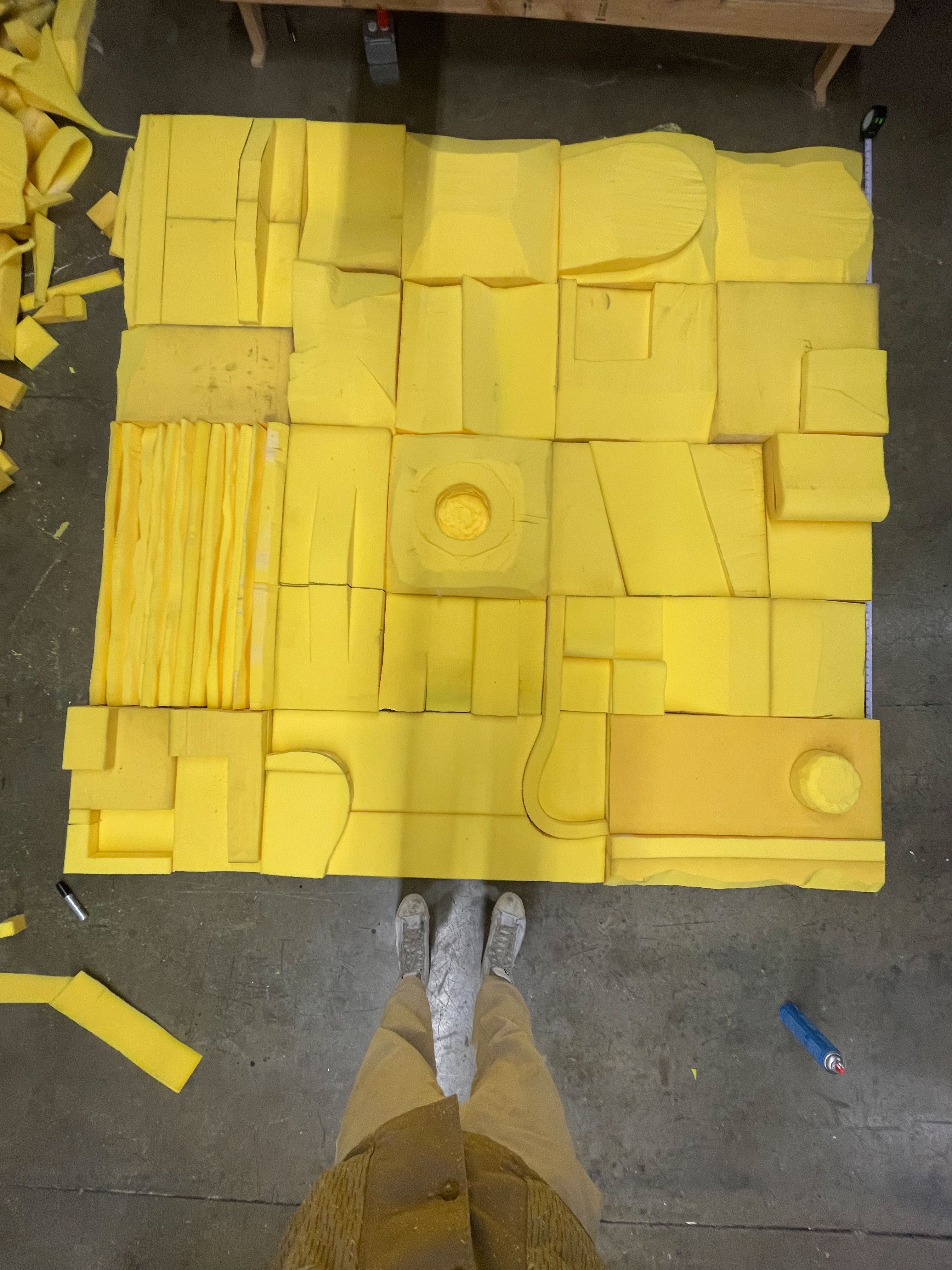a person standing in front of a large yellow foam sculpture