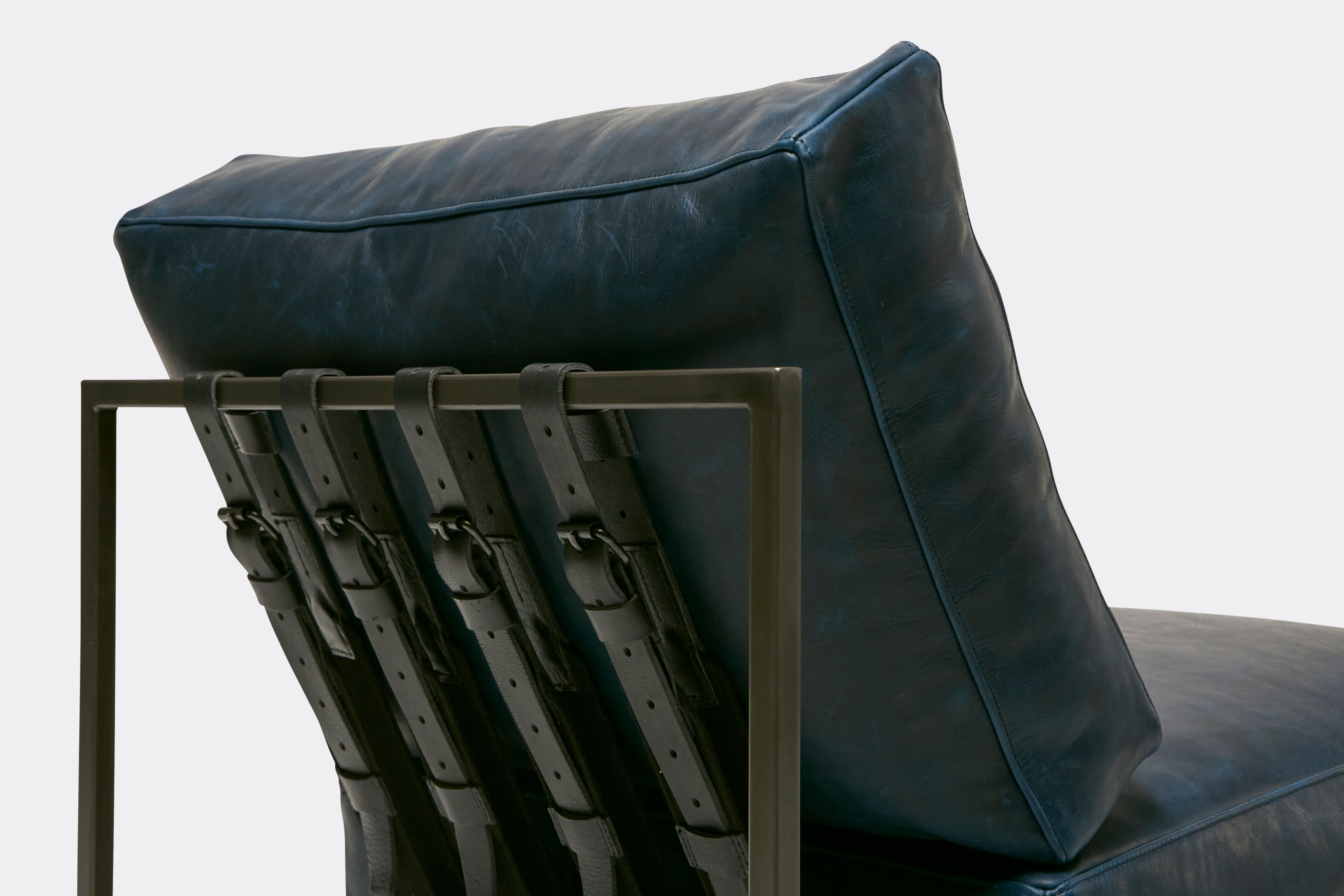 back detail of lounge chair with blue leather upholstery and black leather belts on antique nickel metal frame