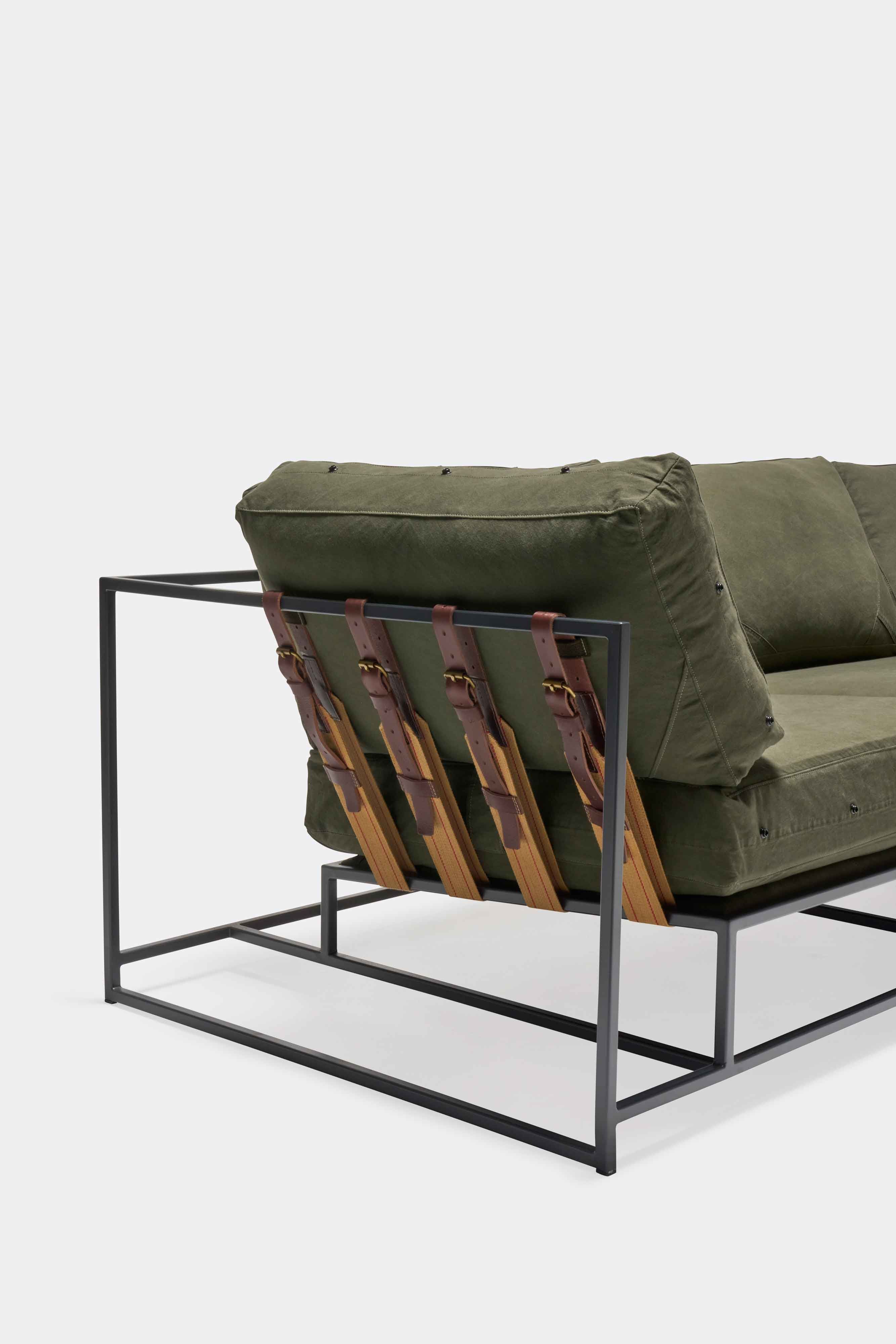 a green couch with a metal frame and leather straps