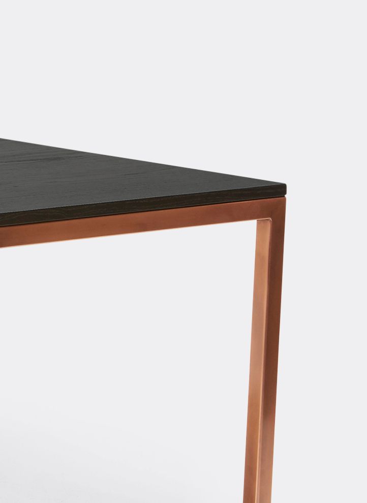a black wood top table with copper finished steel legs shown on a white background .