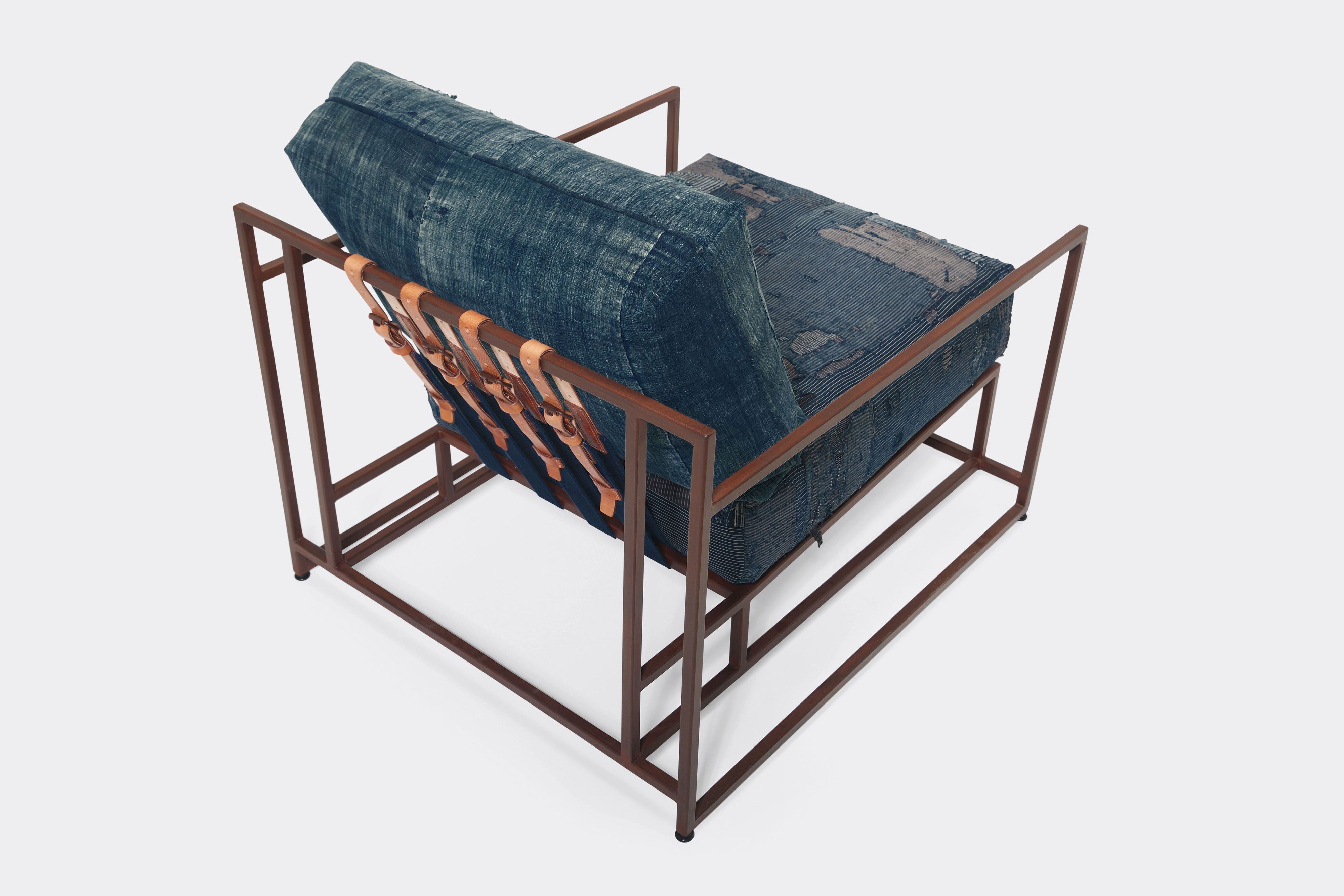 overhead of armchair with vintage boro upholstery and brown leather belts on marbled rust metal frame