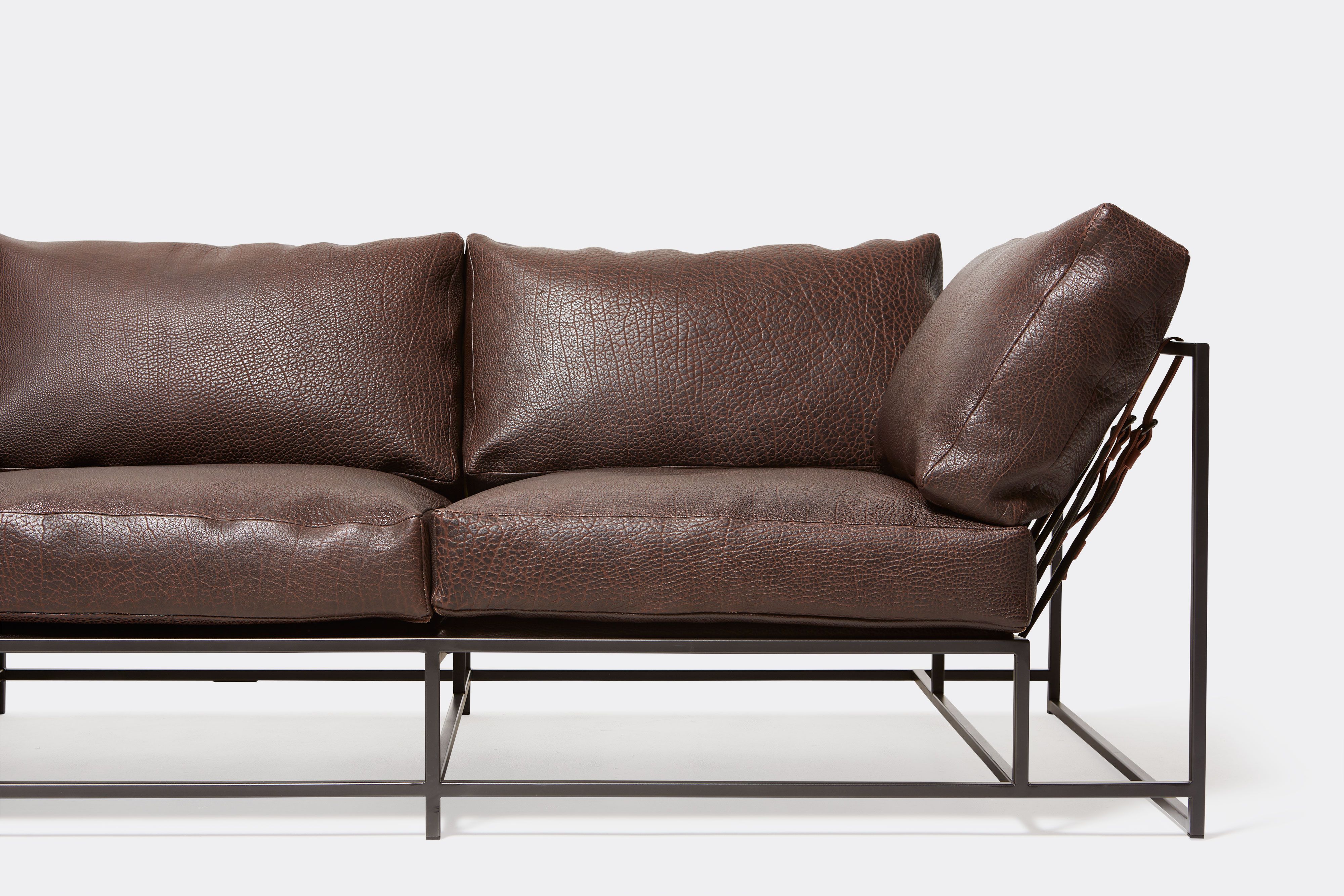 close up front view of brown leather sofa with blacken steel metal frame and leather belts.