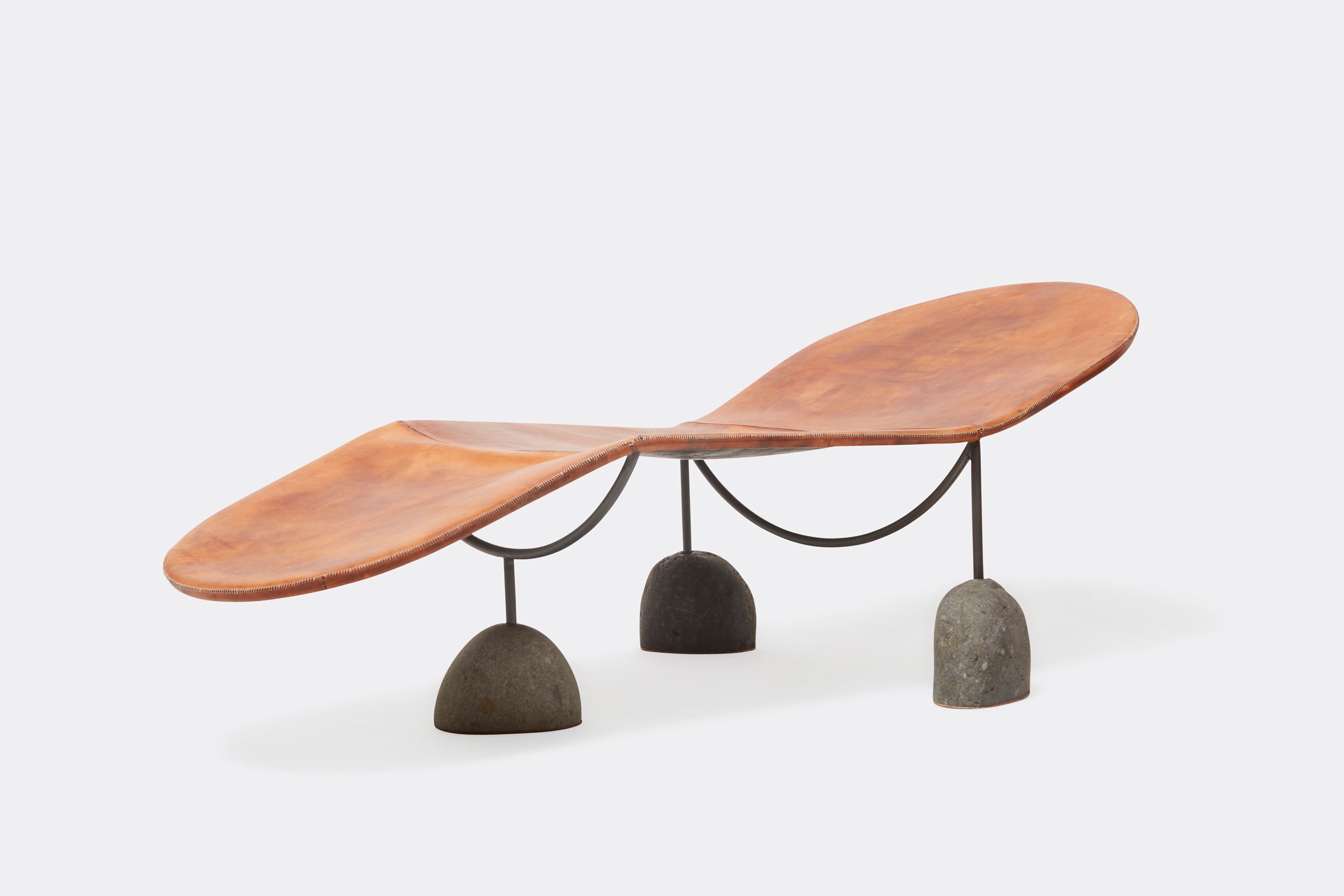 a brown leather chaise lounge with a steel frame and stone base shown on a white background .