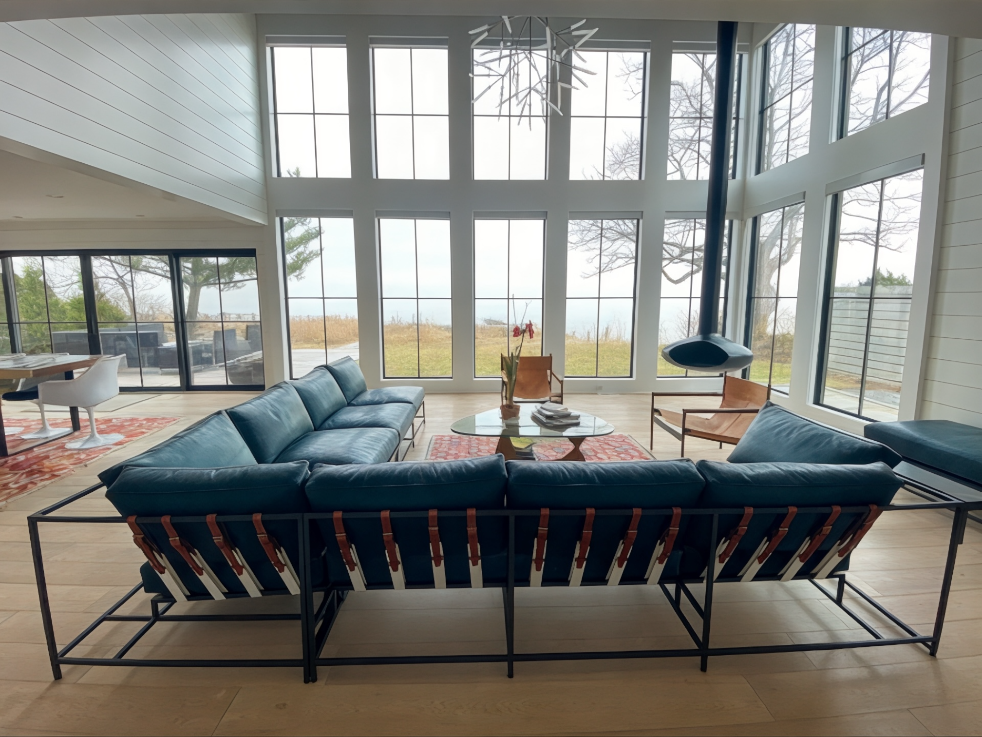 a living room with a large blue leather sectional sofa and large windows looking out onto landscape with grass and trees