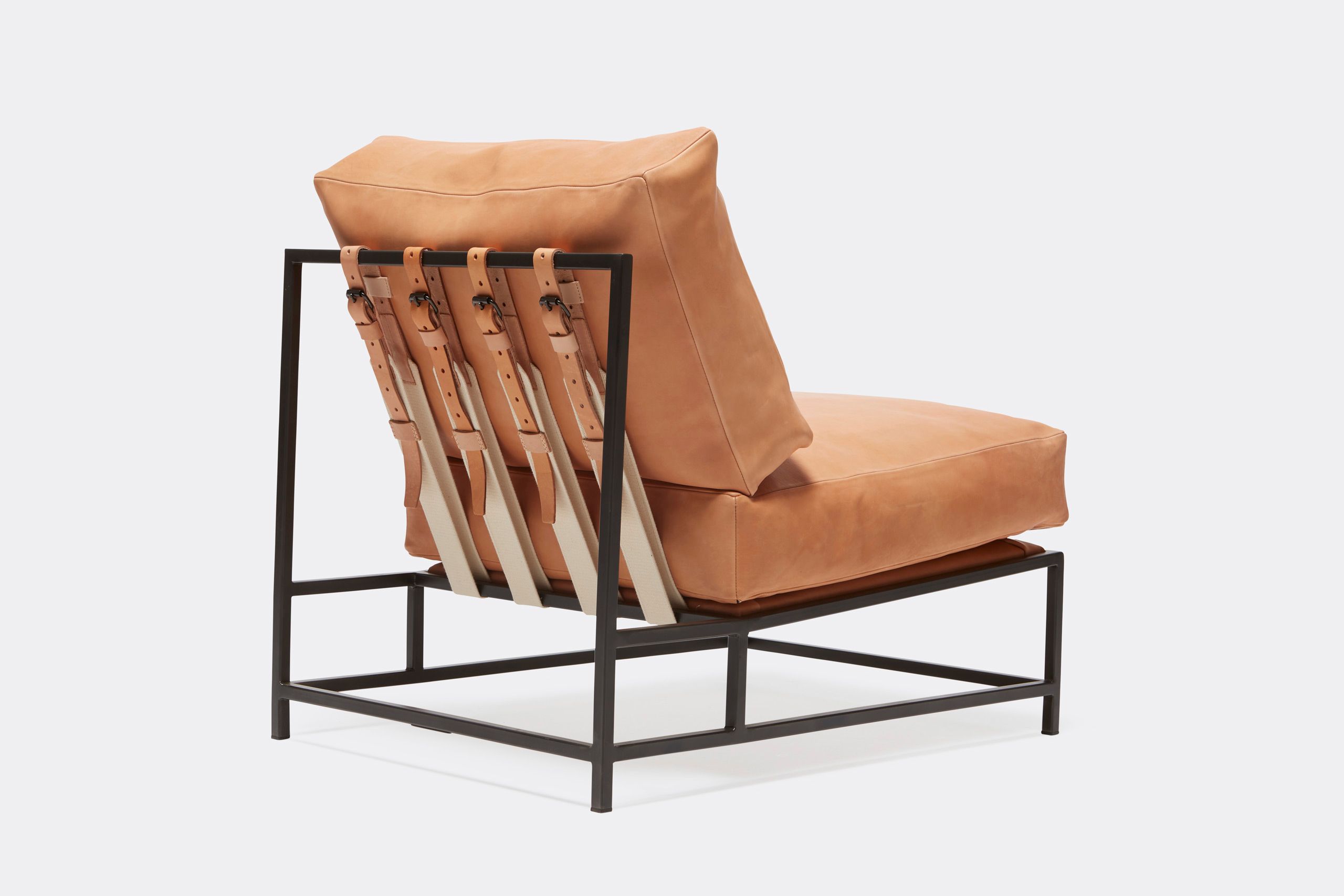 a tan leather chair with a metal frame and leather and webbing supporting belts shown on a white background .