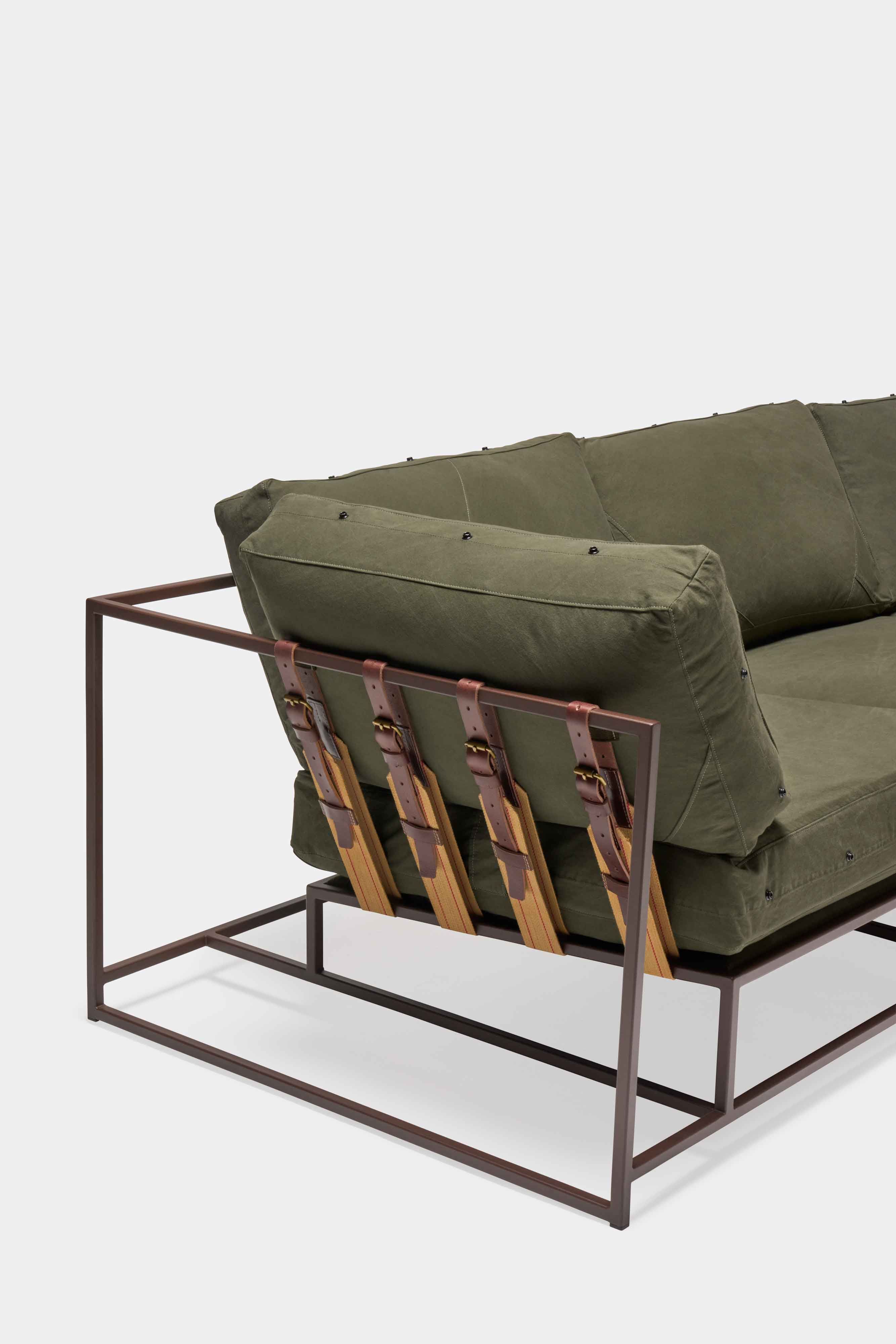 a green couch with a metal frame and leather straps