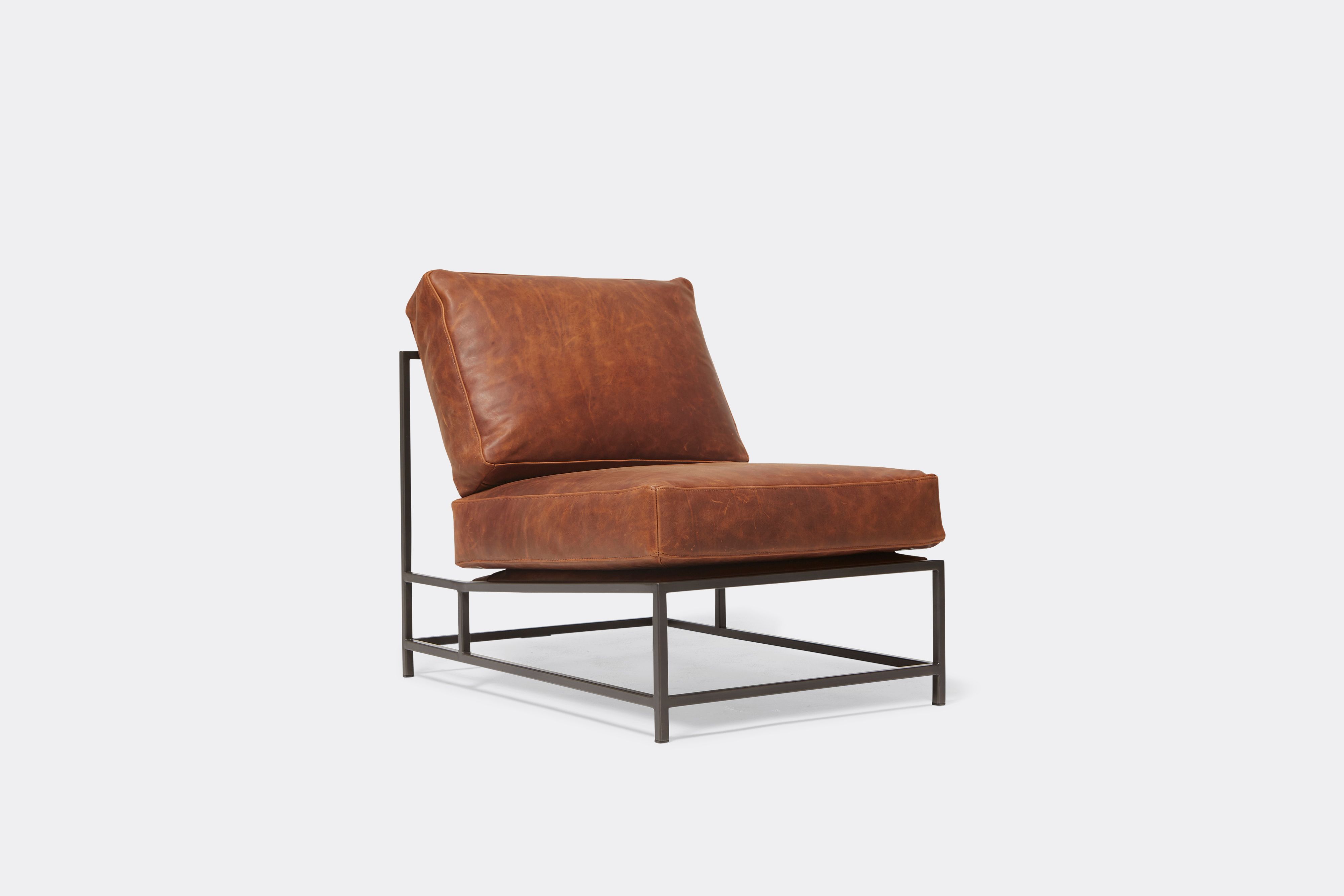 Sideview of lounge chair with brown leather upholstery and black metal frame
