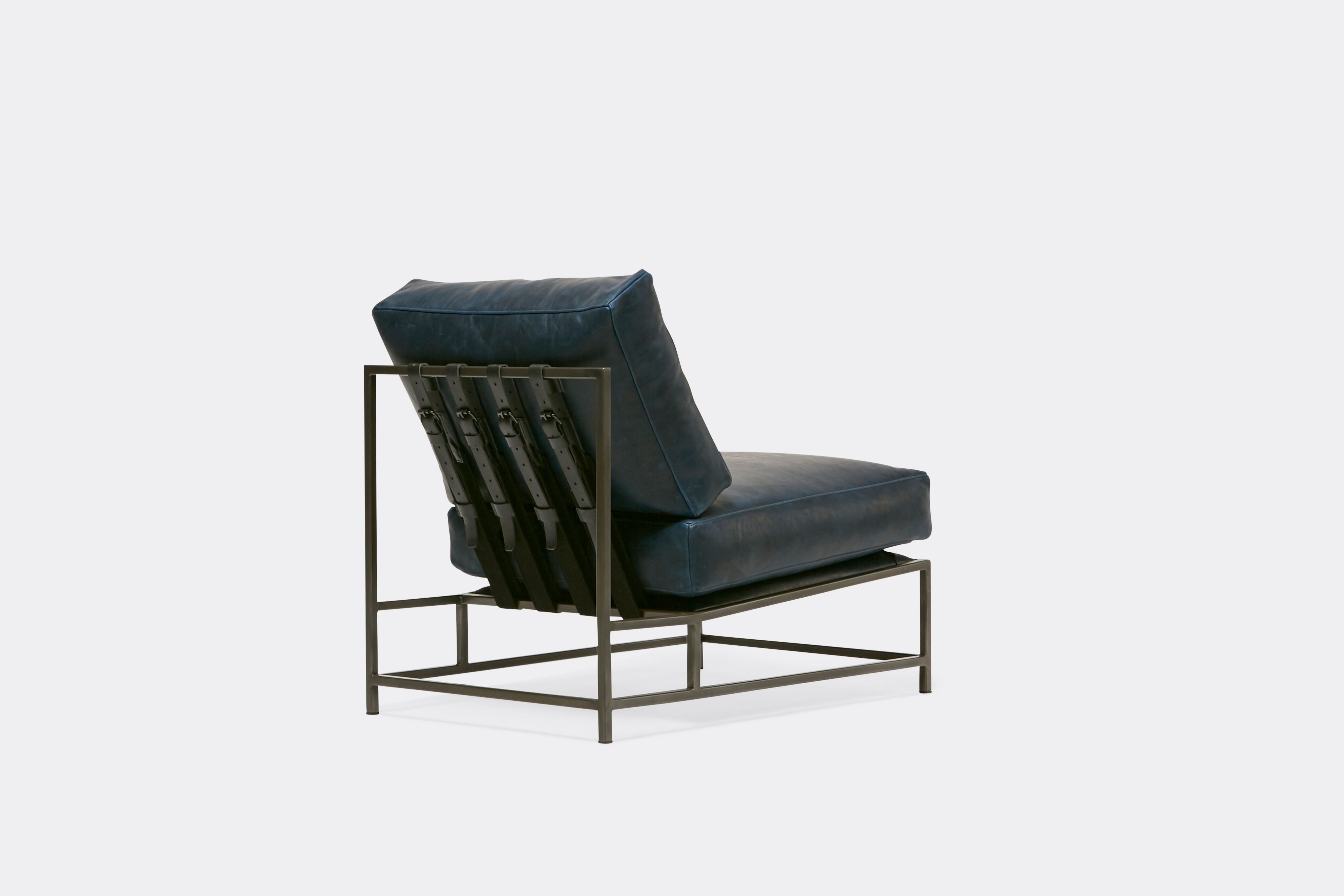 back of lounge chair with blue leather upholstery and black leather belts on antique nickel metal frame