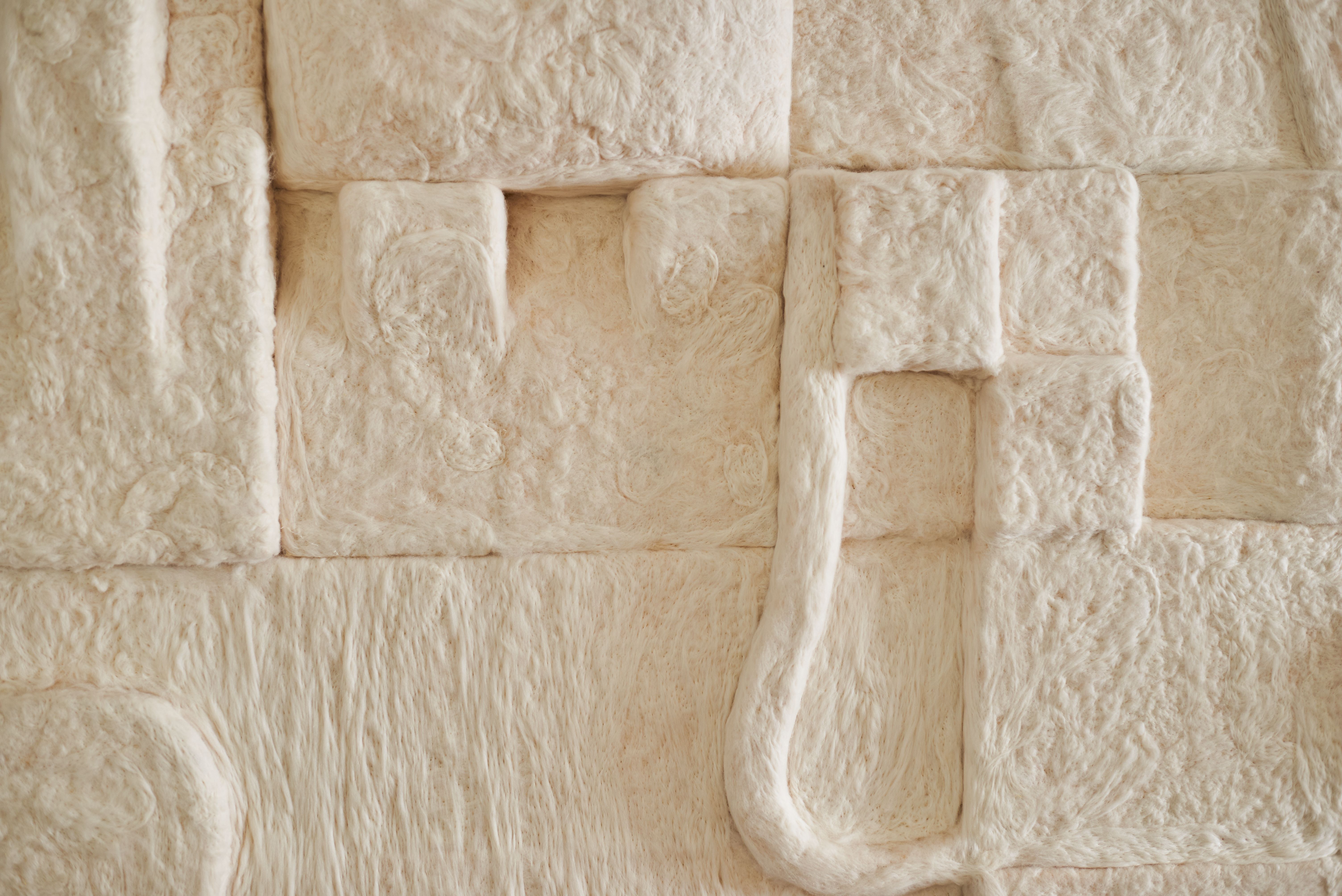 a close up of a white wool sculpture on a wall .