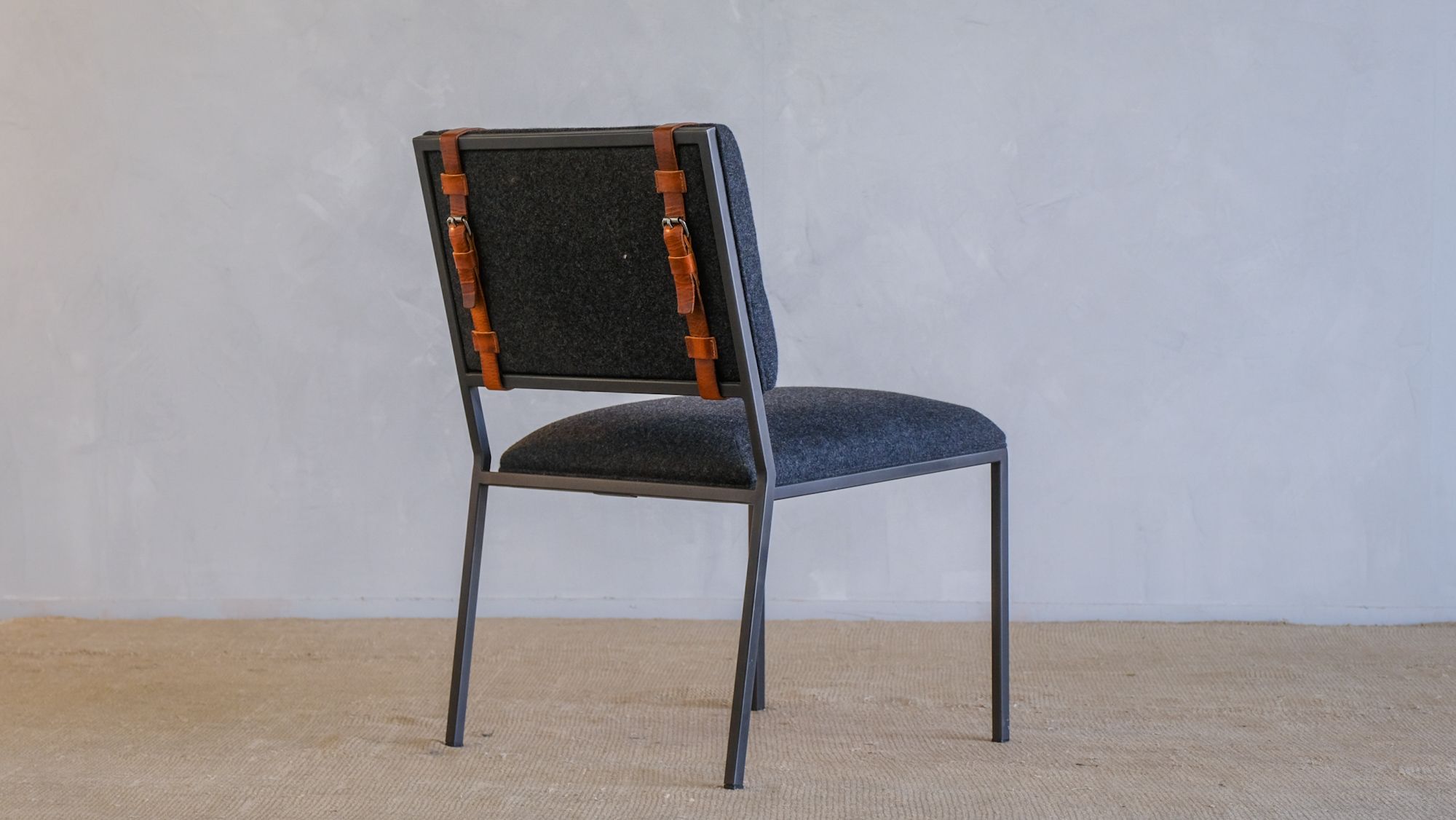 the back of a chair with leather straps on it is sitting on a carpet .