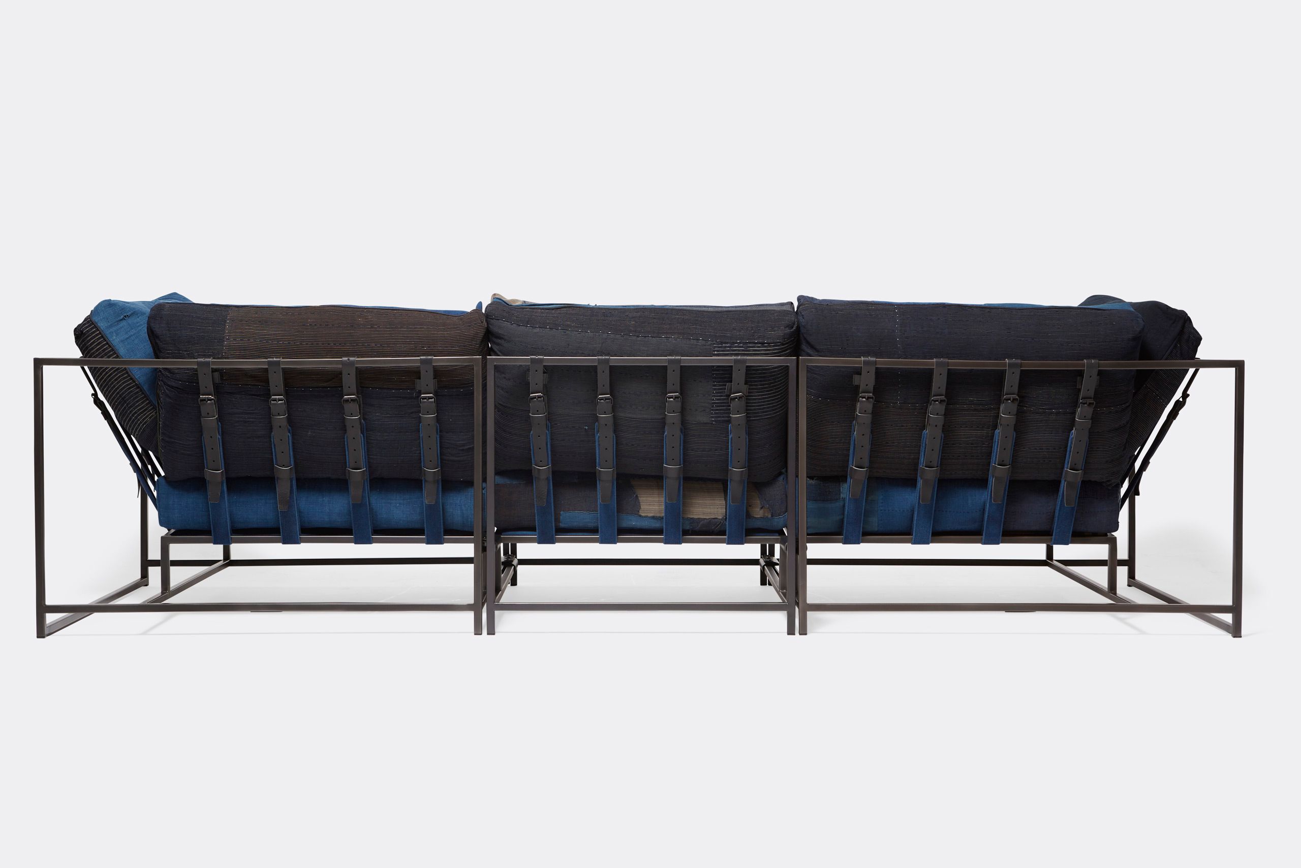 A steel framed sofa with vintage Japanese indigo and grey upholstery and supporting belts shown on a white background