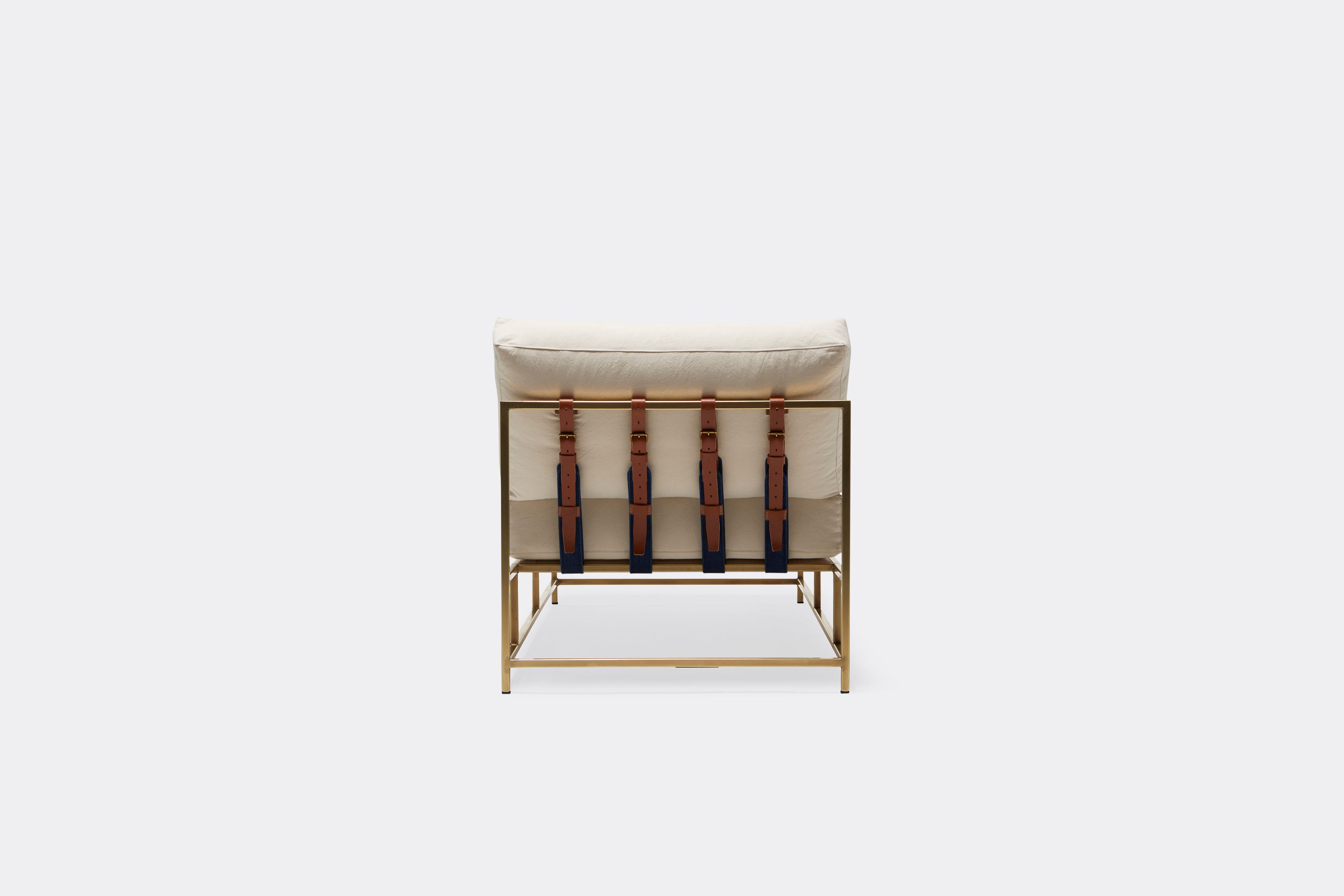 Back of lounge chaise with natural canvas upholstery and brown leather belt on tarnished brass metal frame
