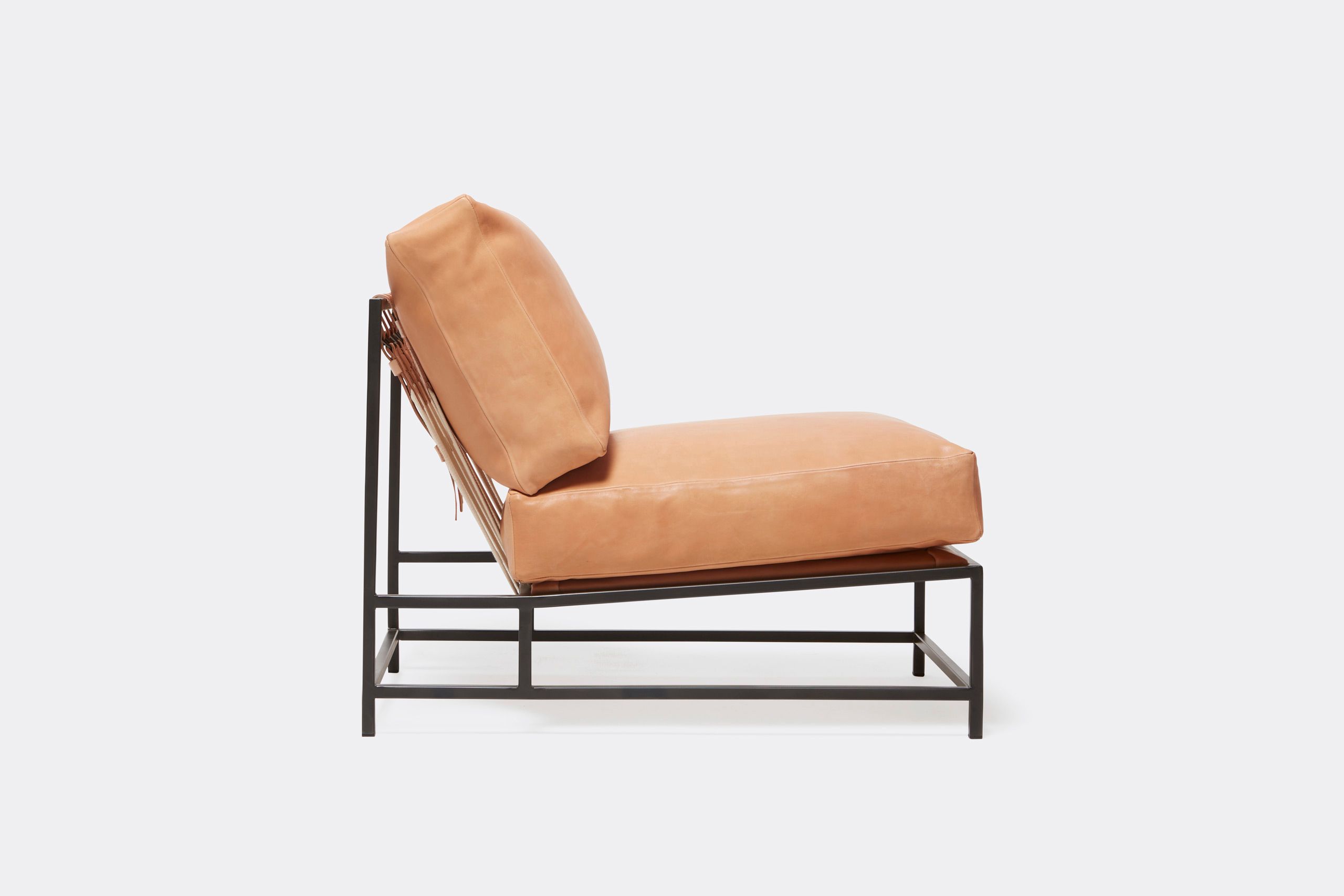 a tan leather chair with a metal frame and leather and webbing supporting belts shown on a white background .