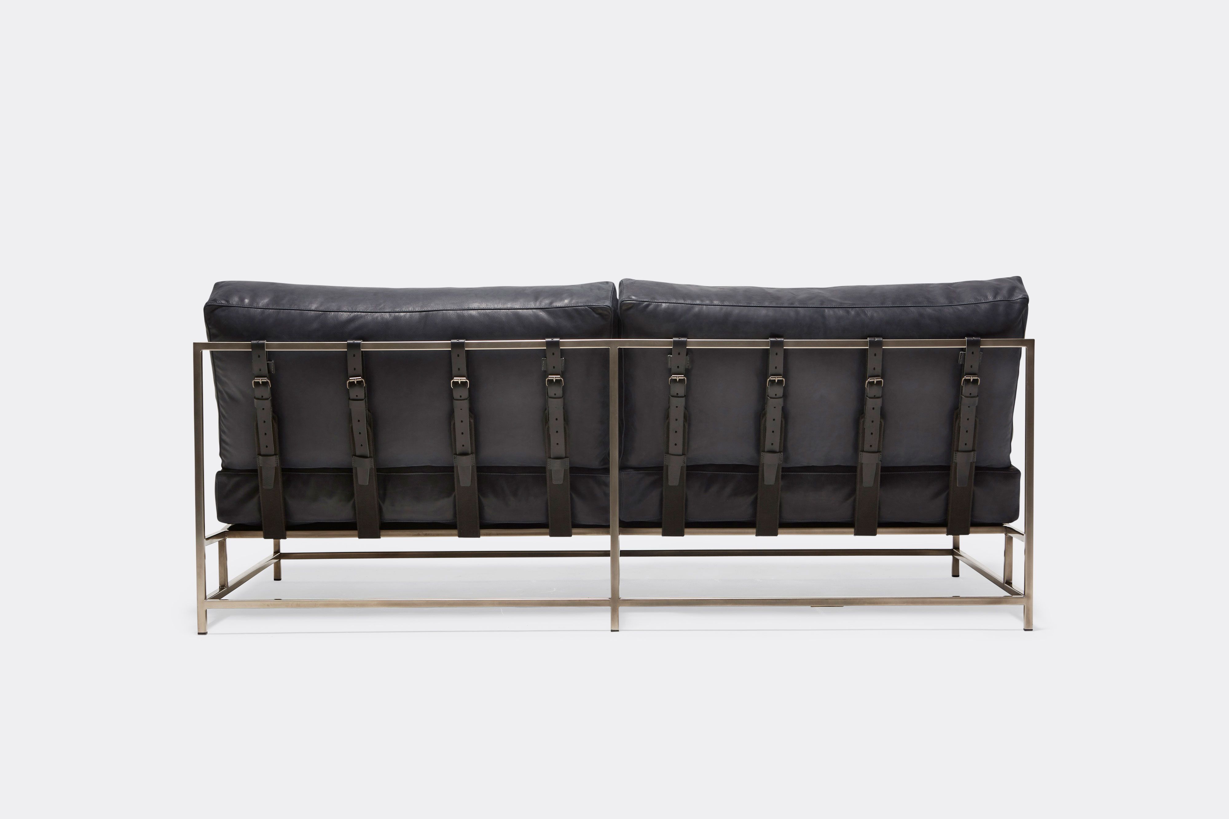 side of loveseat with blue leather upholstery and black leather belts on antique nickel metal frame