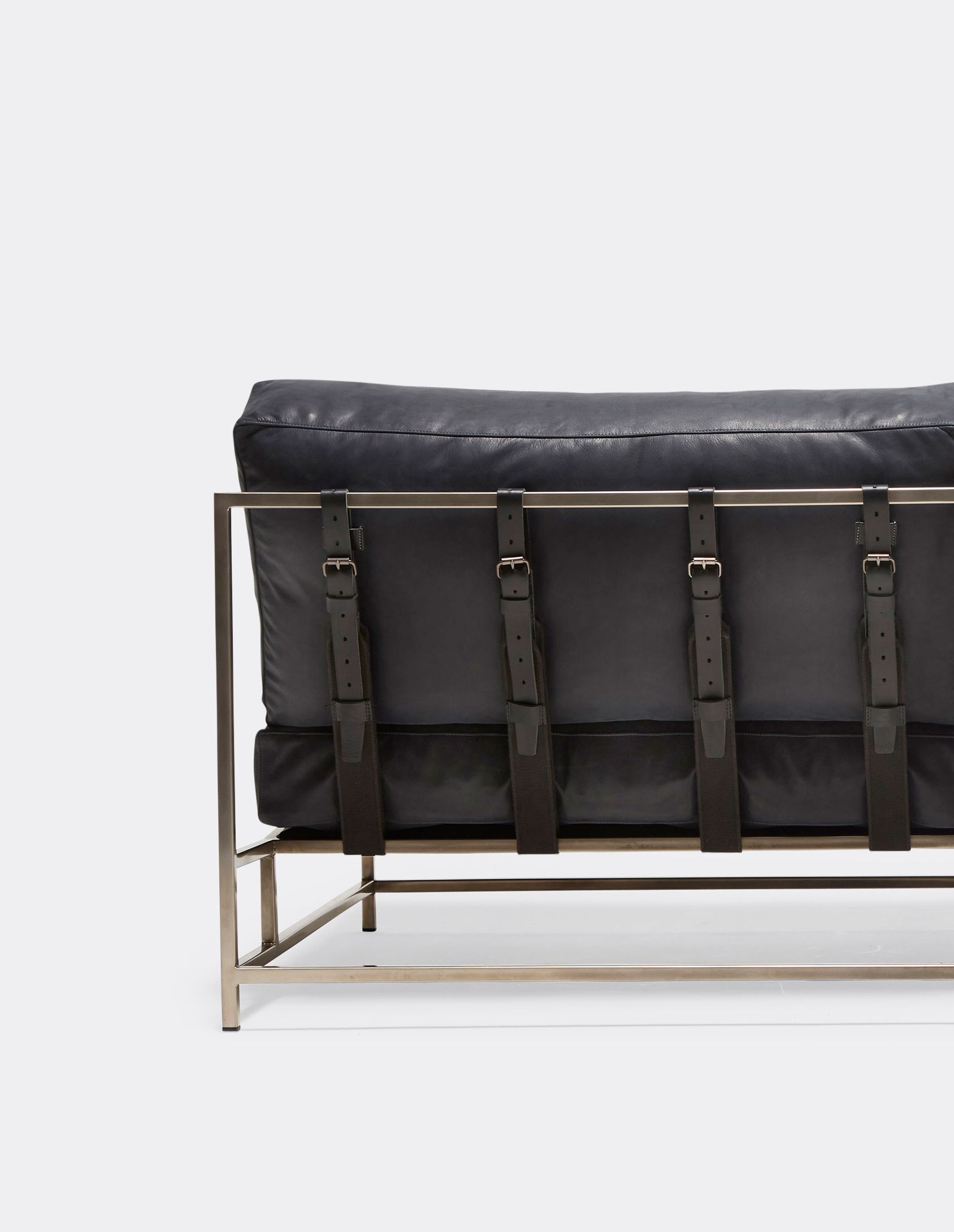 a dark blue leather loveseat sofa with a blackened steel frame and black leather and webbing belts shown on a white background .