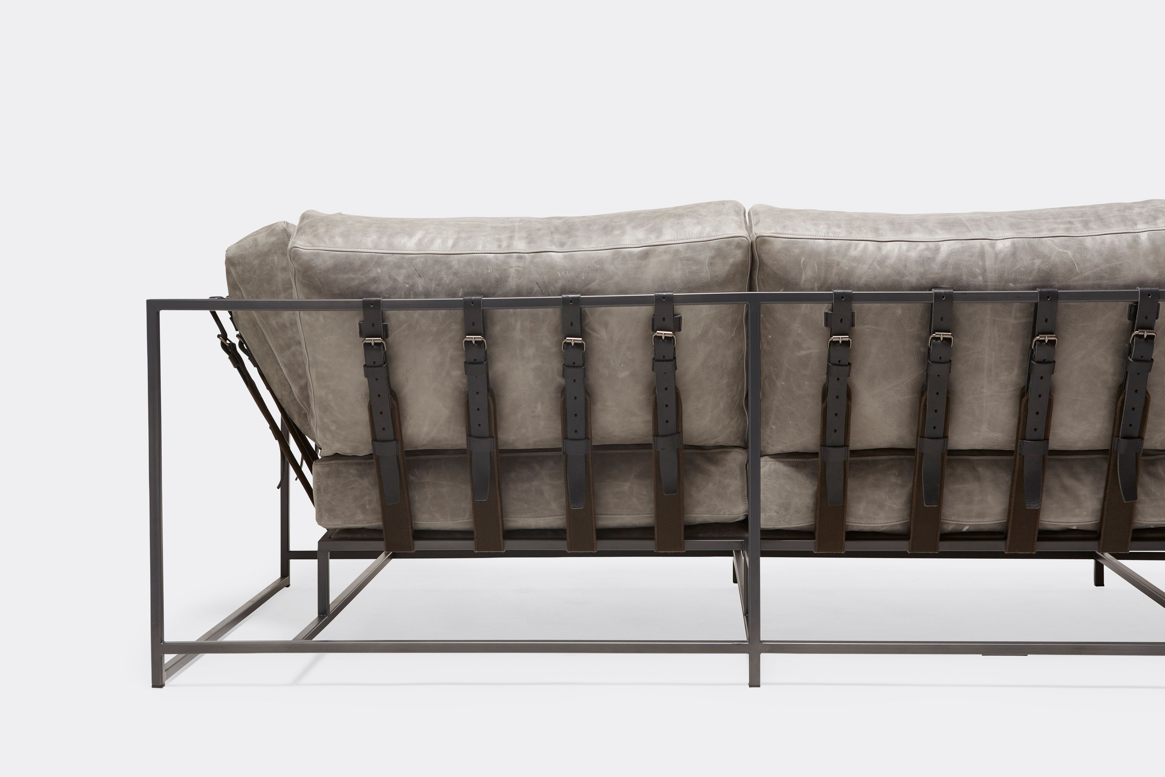 back of Sofa with gray leather upholstery and black leather belts on gray powdercoat metal frame