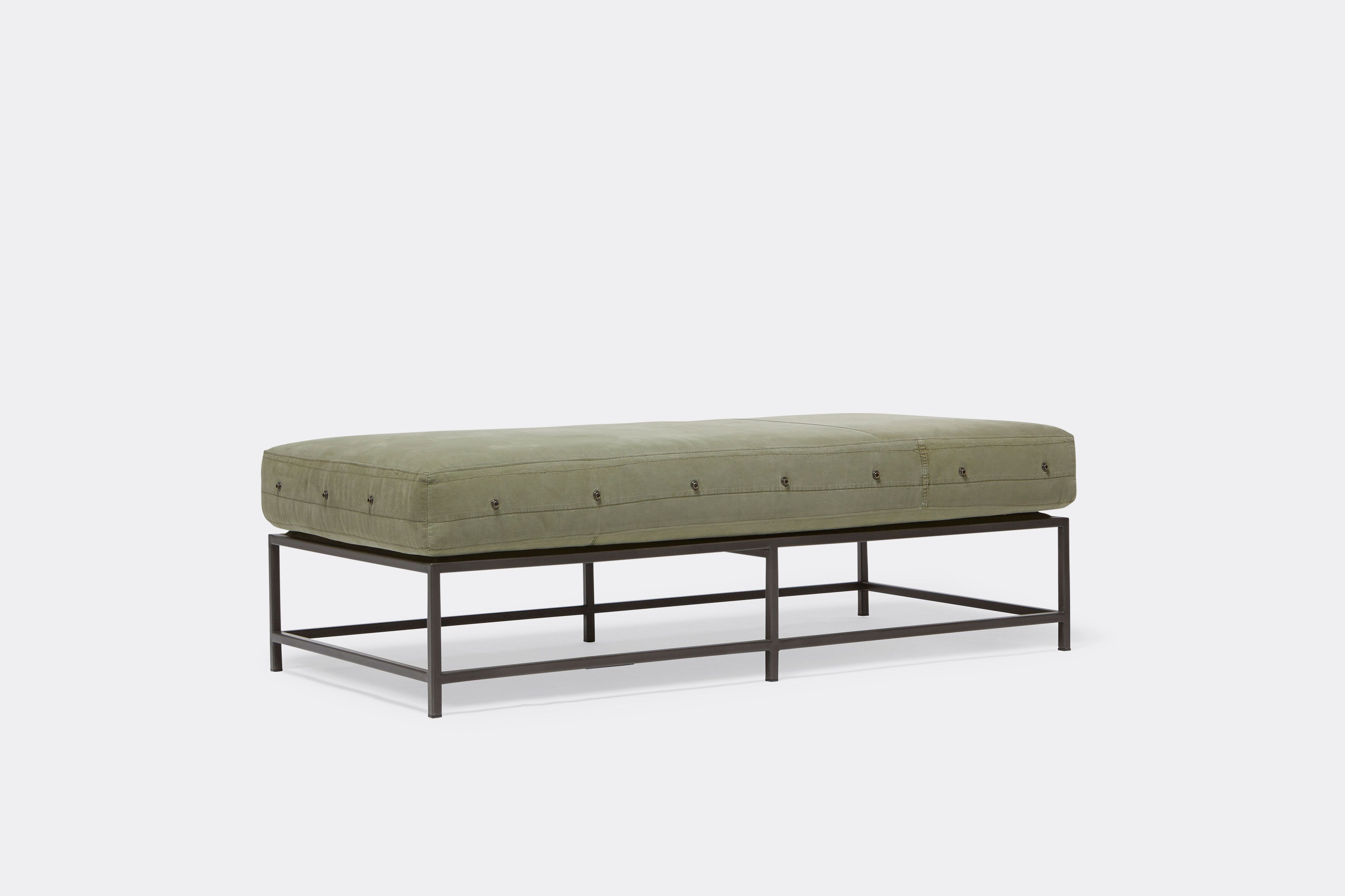 front of bench with green canvas upholstery on black metal frame.