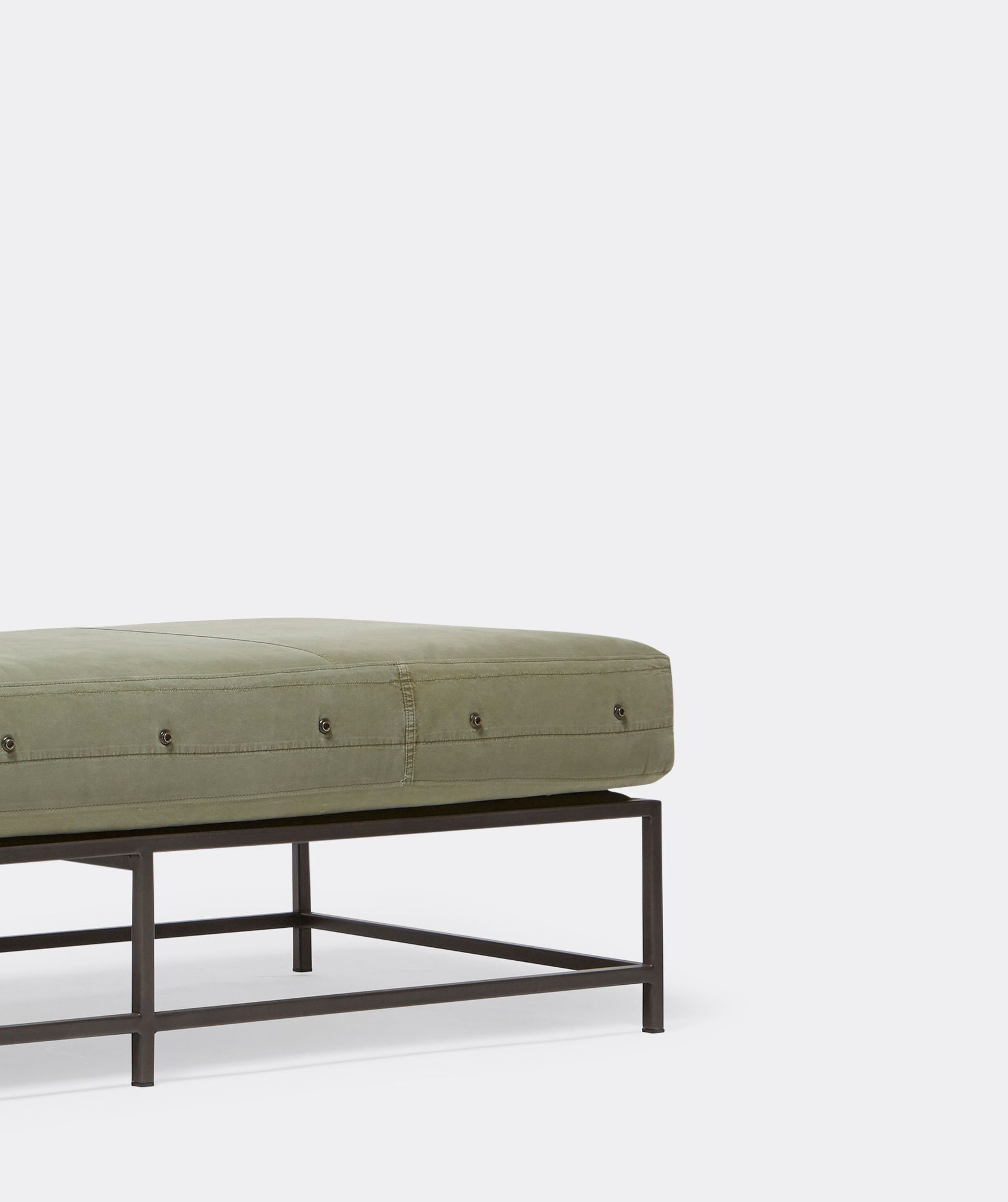 a bench with a green cushion and a metal frame on a white background .