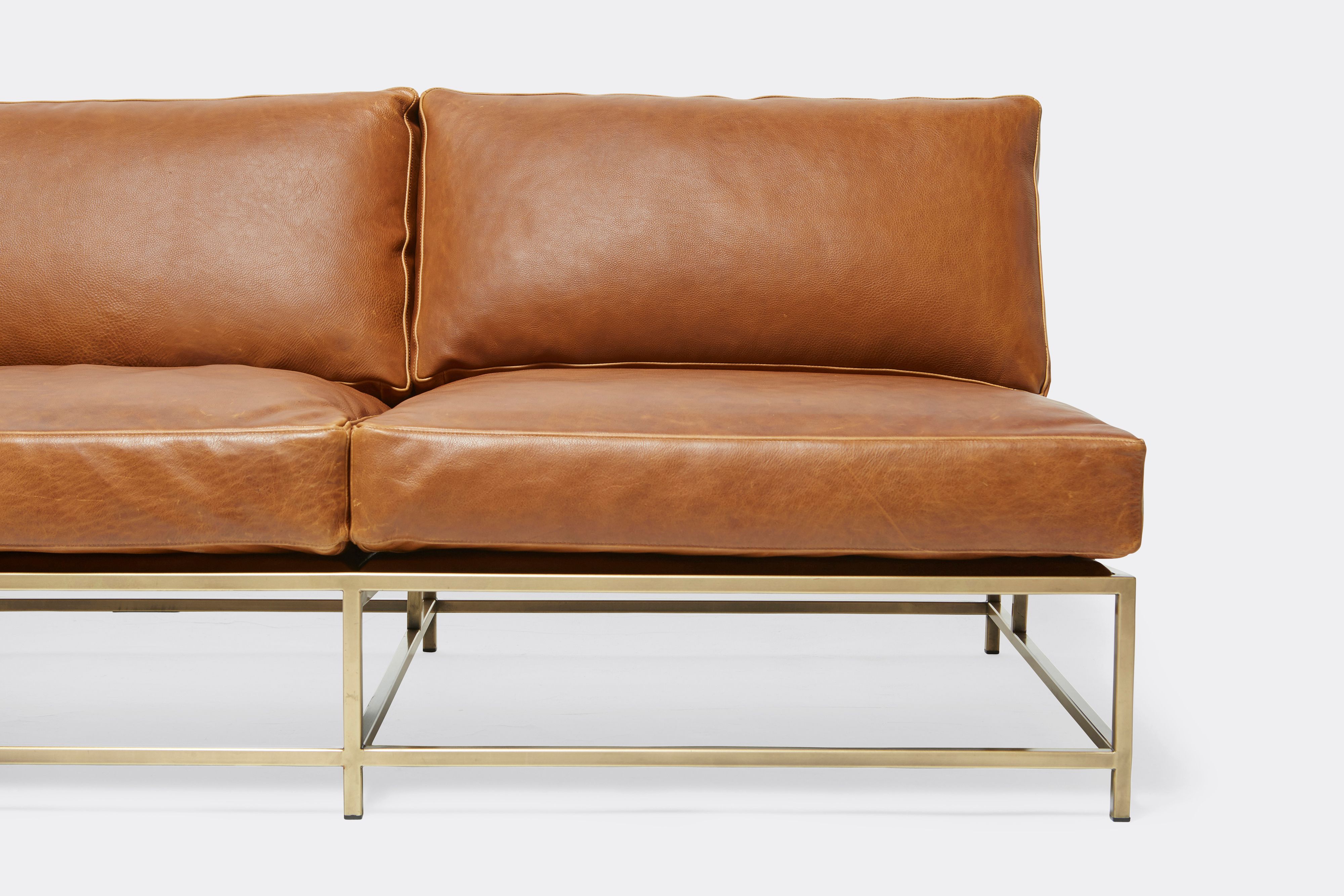 front detail of loveseat with brown leather upholstery on antique brass metal frame